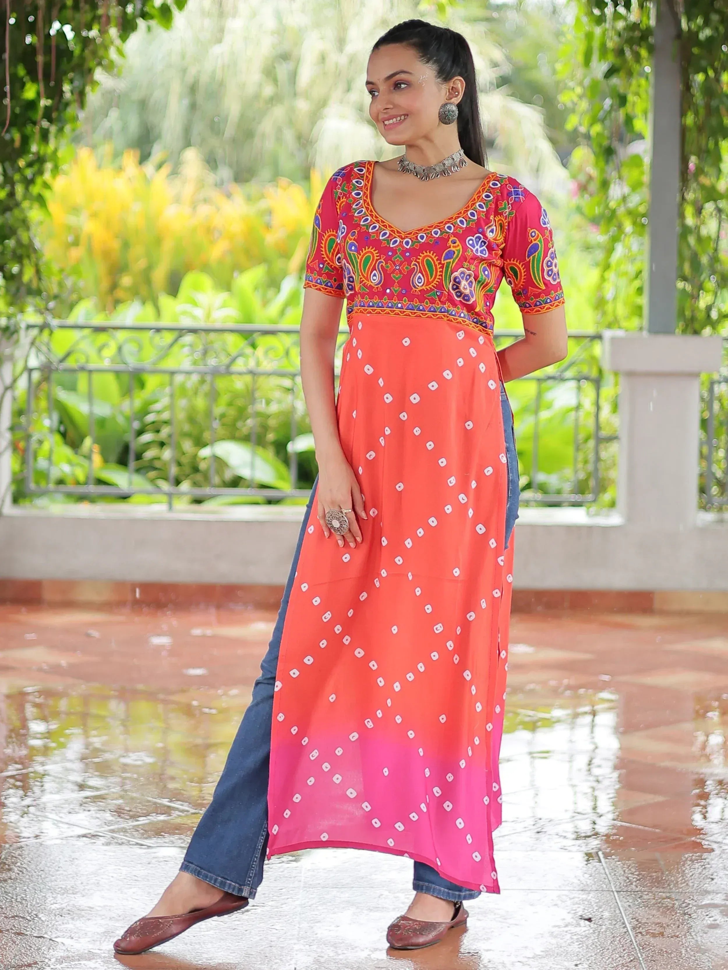 Woman in vibrant embroidered ethnic kurta with bandhani print, paired with jeans, perfect for casual Indian wear