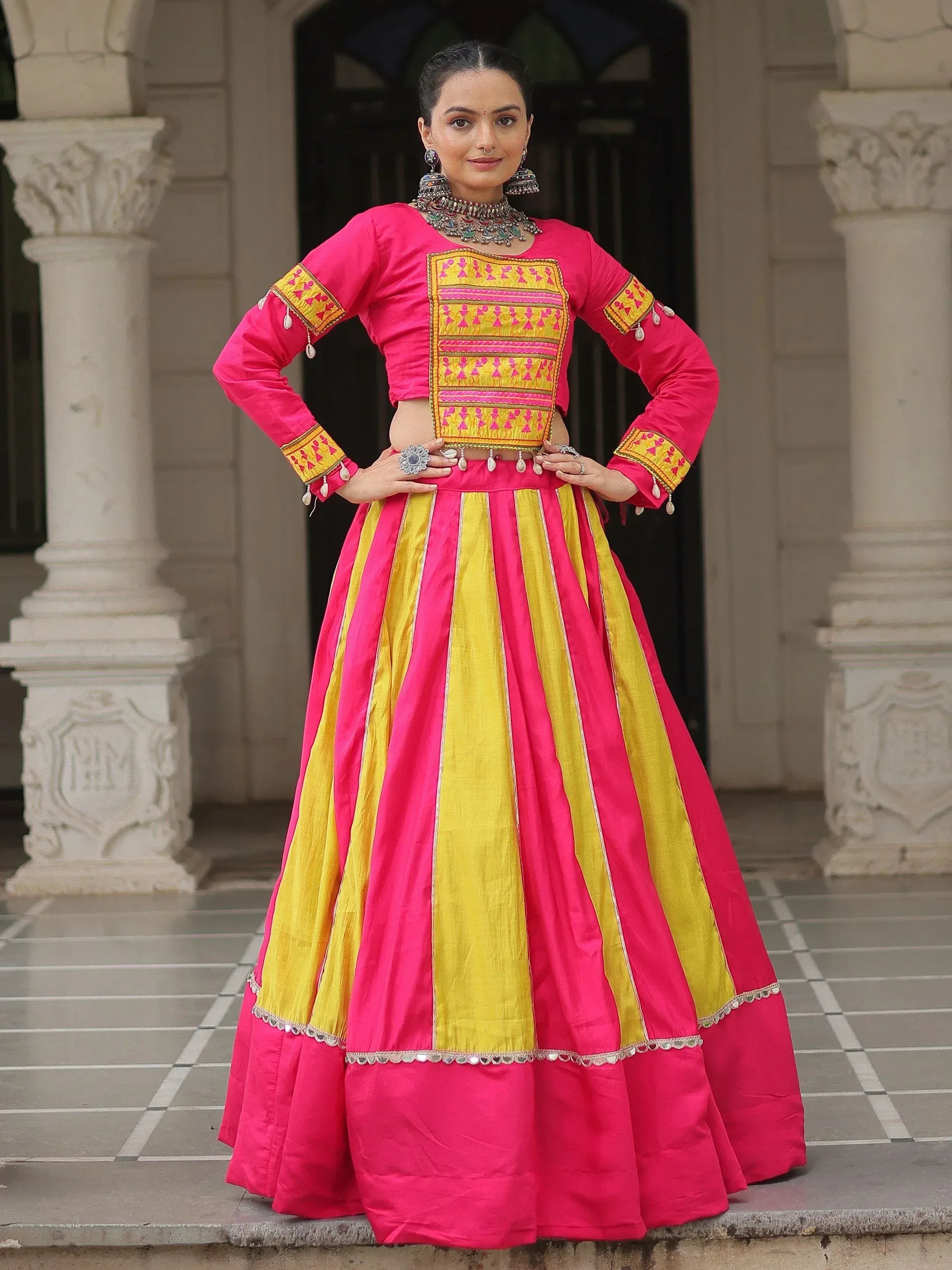 Vibrant pink and yellow ethnic lehenga choli with intricate embroidery and traditional jewelry