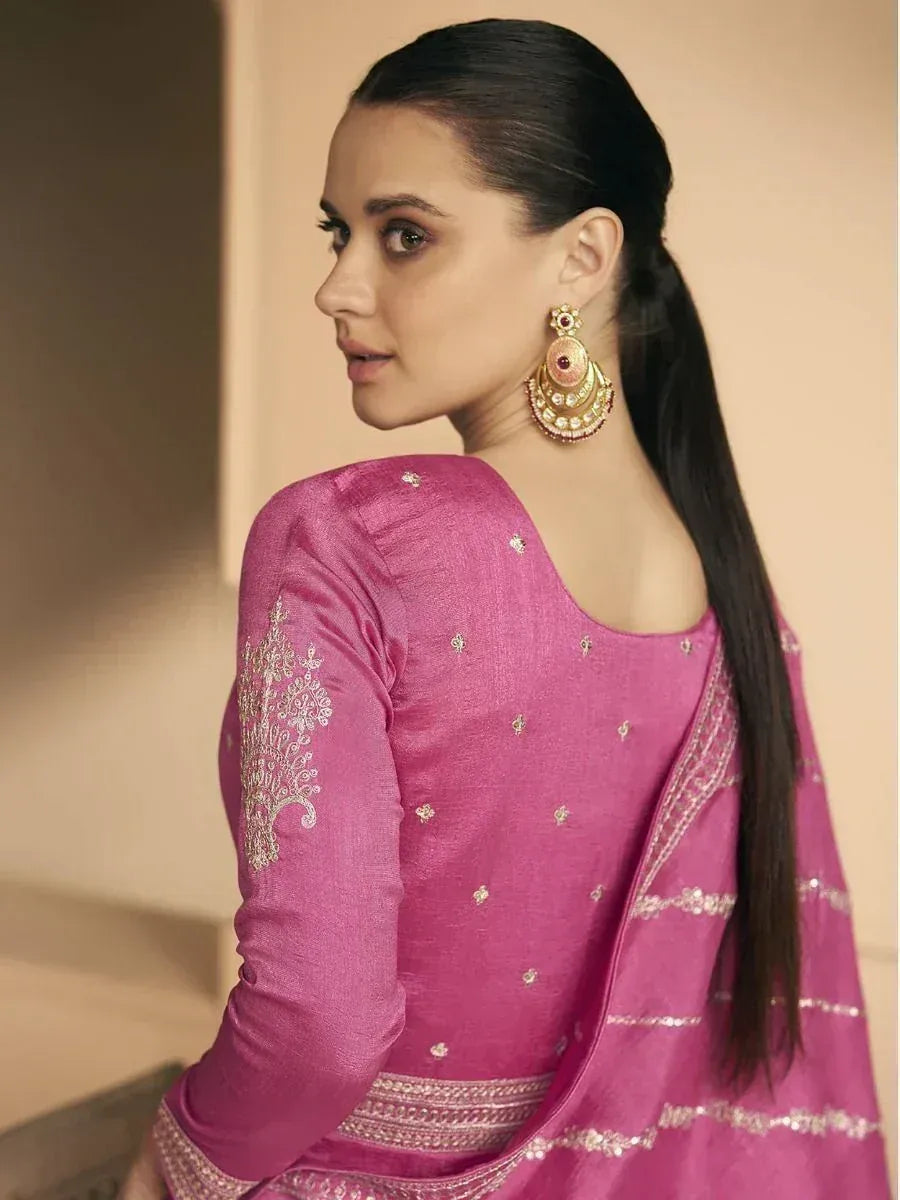 Pink embroidered salwar kameez with gold detailing and statement earrings, ideal for ethnic occasions