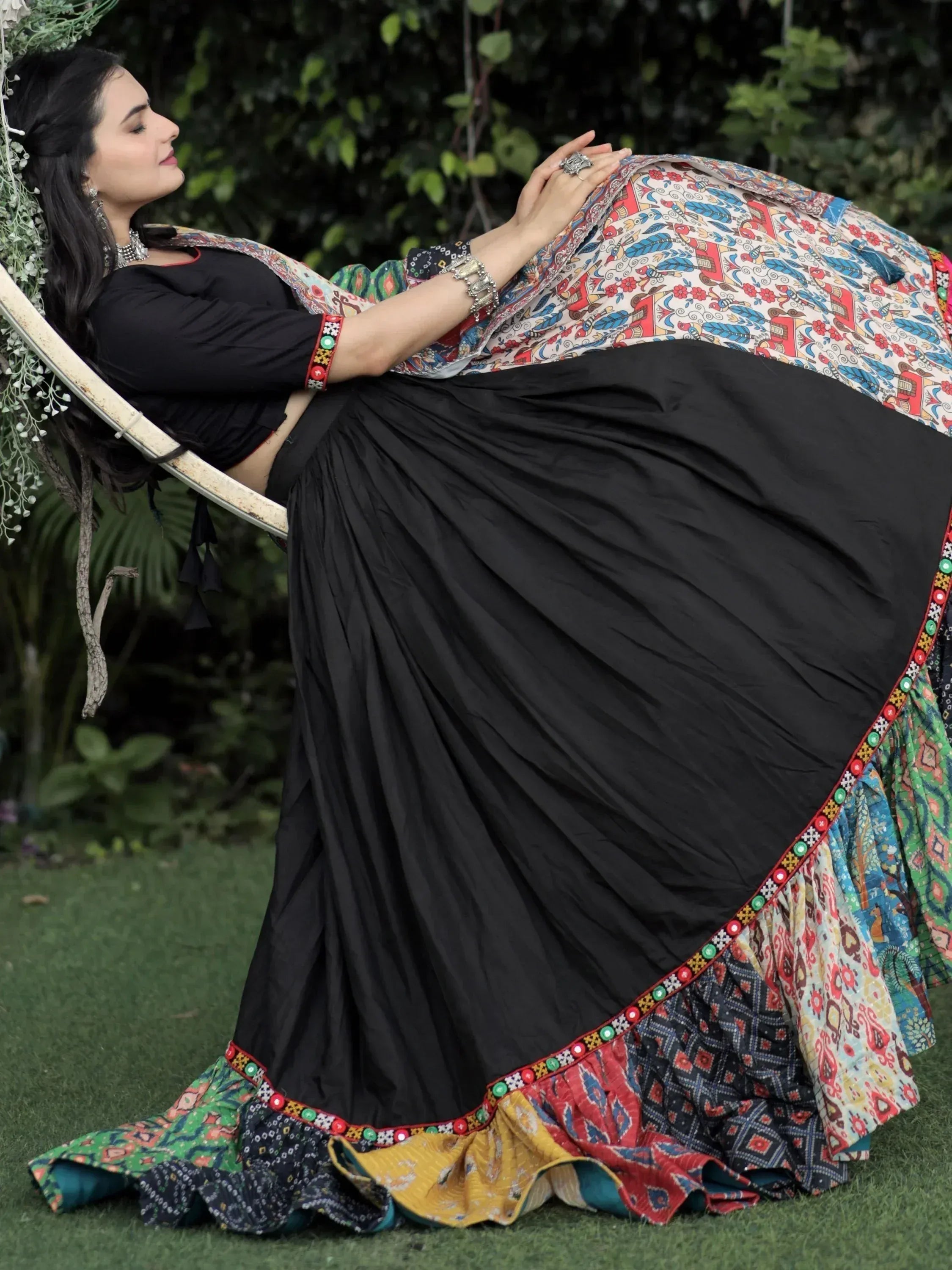 Woman in black ethnic skirt with colorful printed dupatta, relaxing outdoors