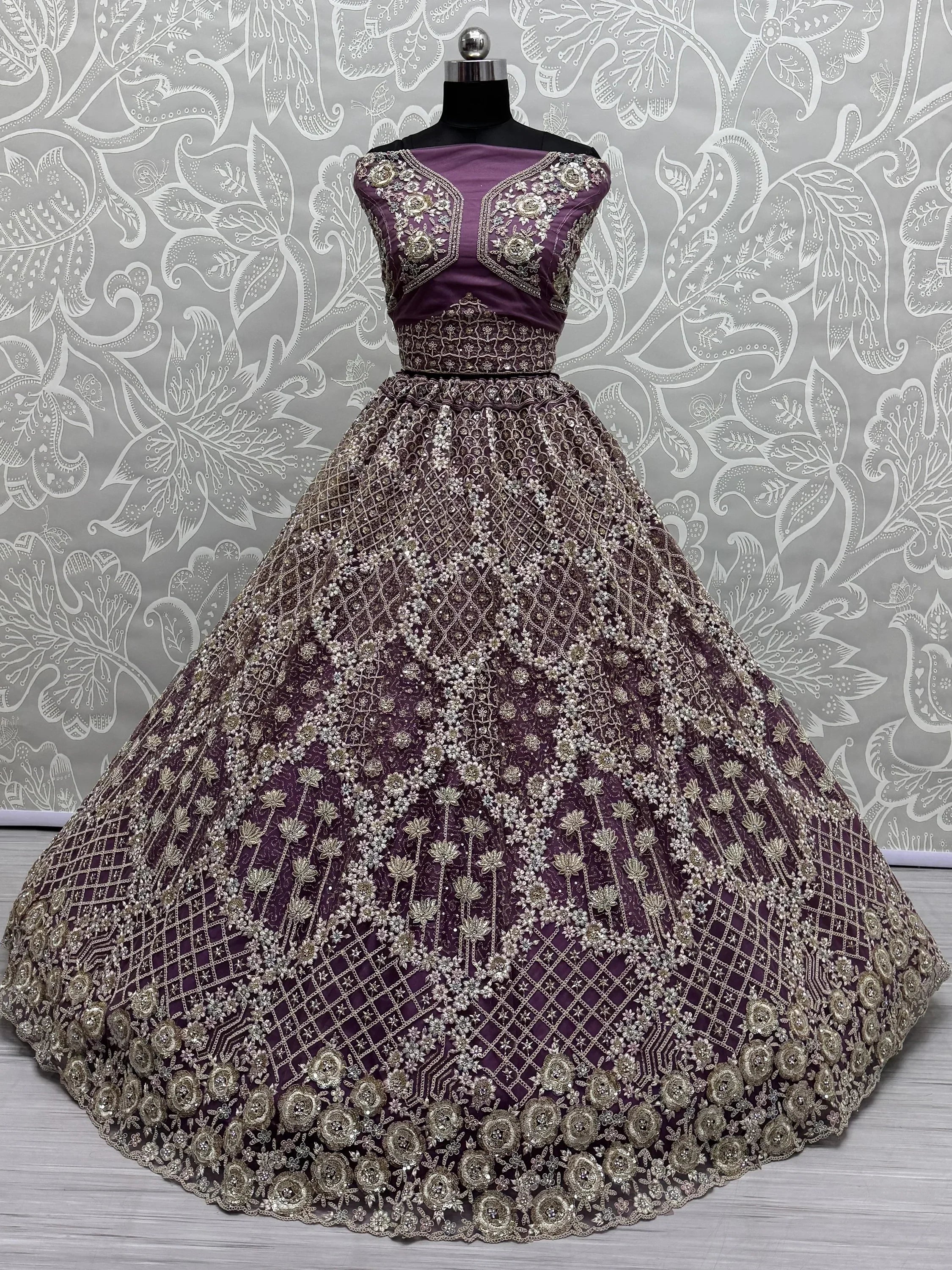 Purple designer lehenga choli with heavy gold embroidery and floral motifs, perfect for weddings and festive occasions.