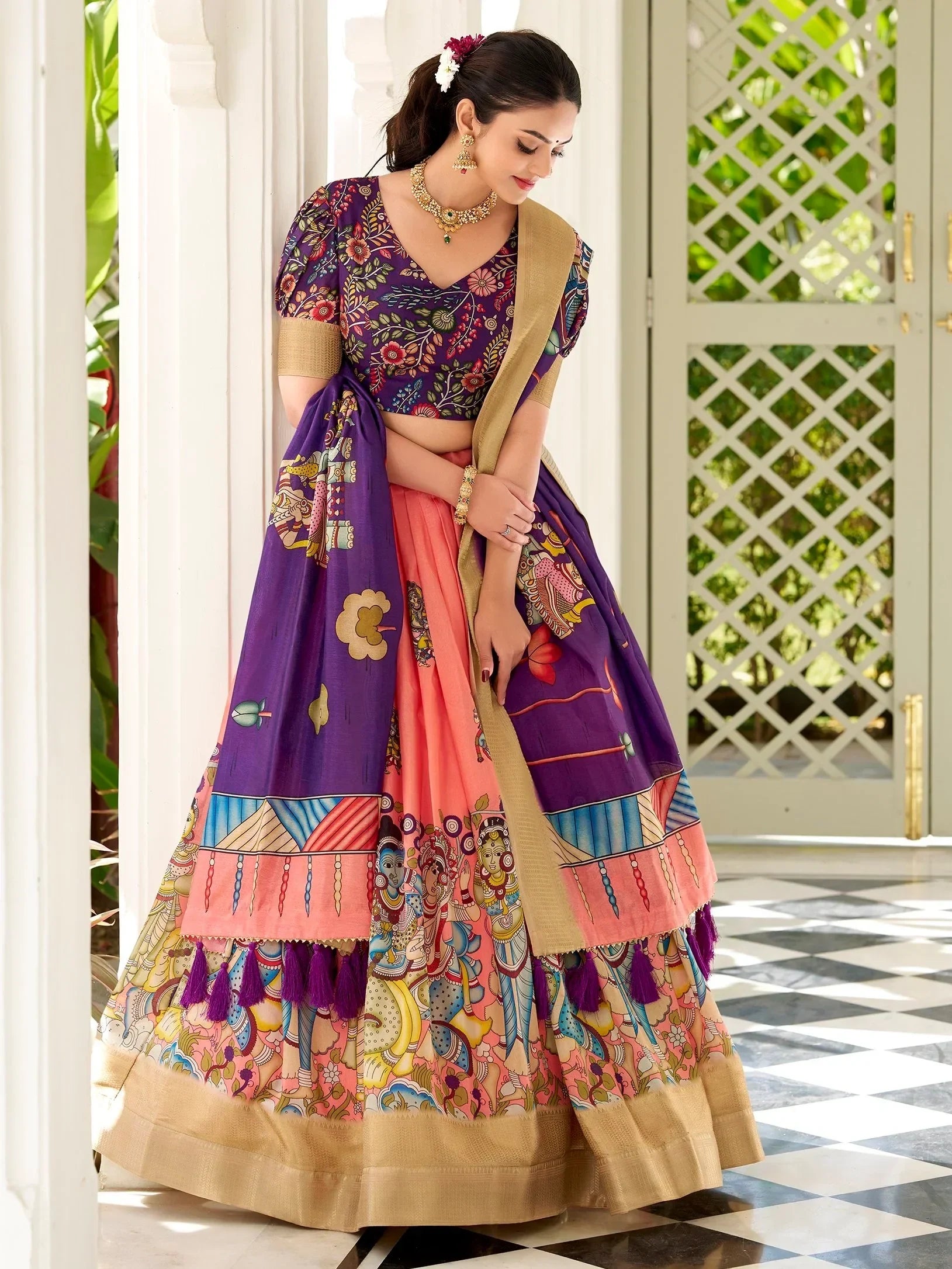Woman in vibrant purple and pink printed lehenga choli with gold border, perfect for Indian ethnic wear occasions