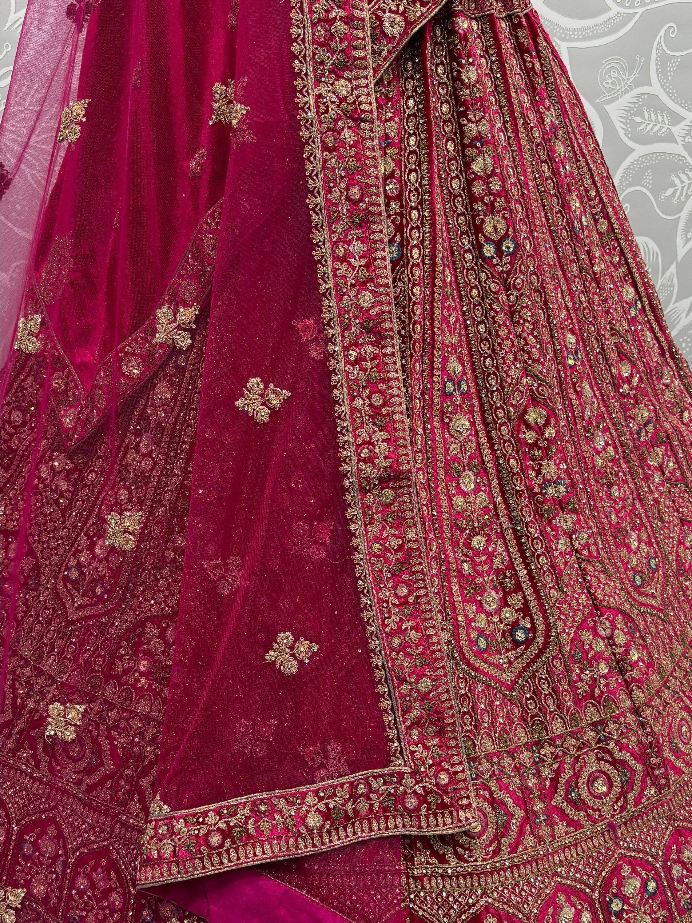 Rich maroon velvet lehenga choli with intricate gold embroidery and embellished dupatta, perfect for Indian weddings.