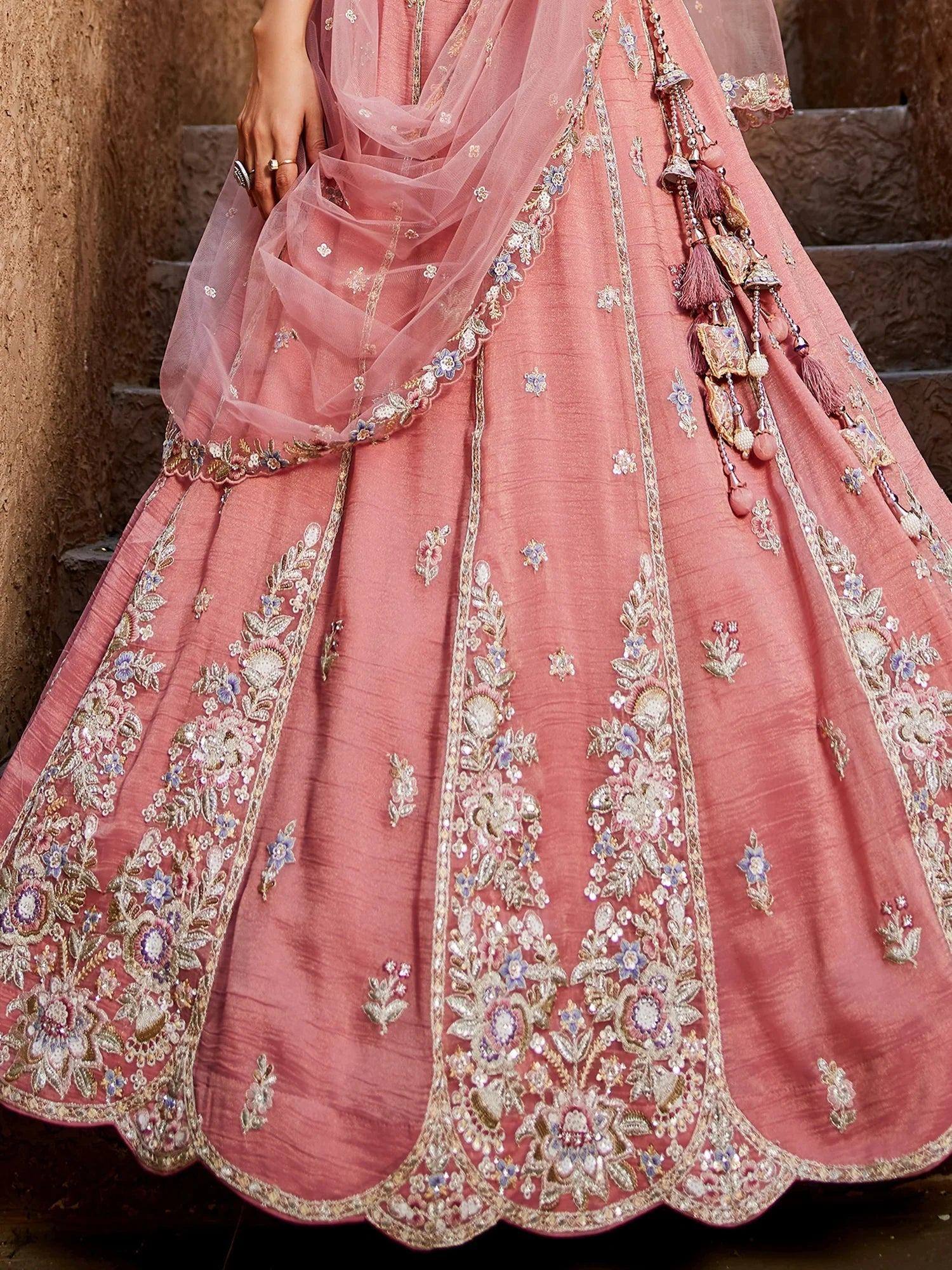 Pink embroidered lehenga choli with floral motifs and tassels, perfect for Indian weddings and festive occasions.