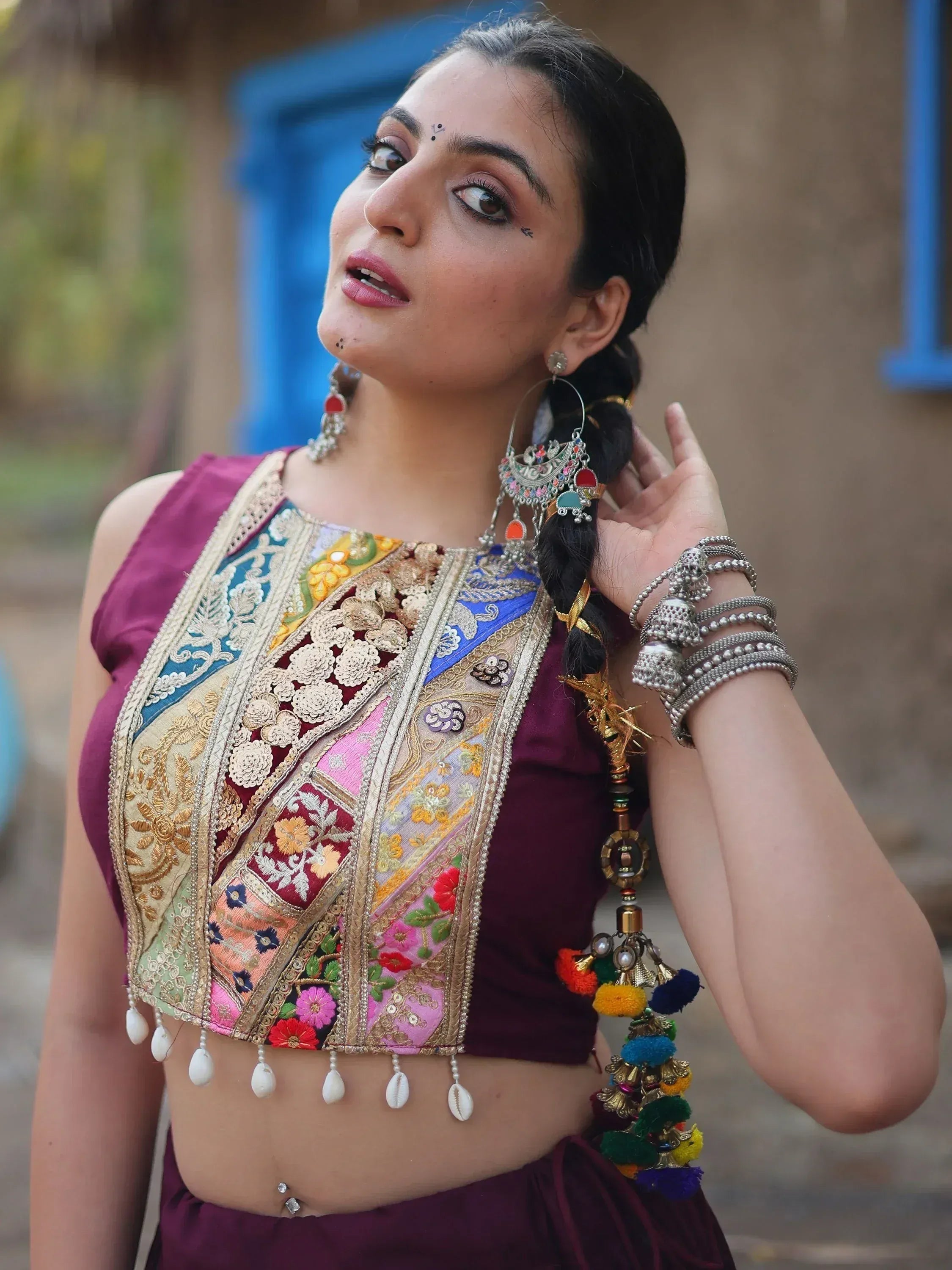 Woman in colorful embroidered Indian ethnic top with mirror work, pom-poms, and traditional jewelry