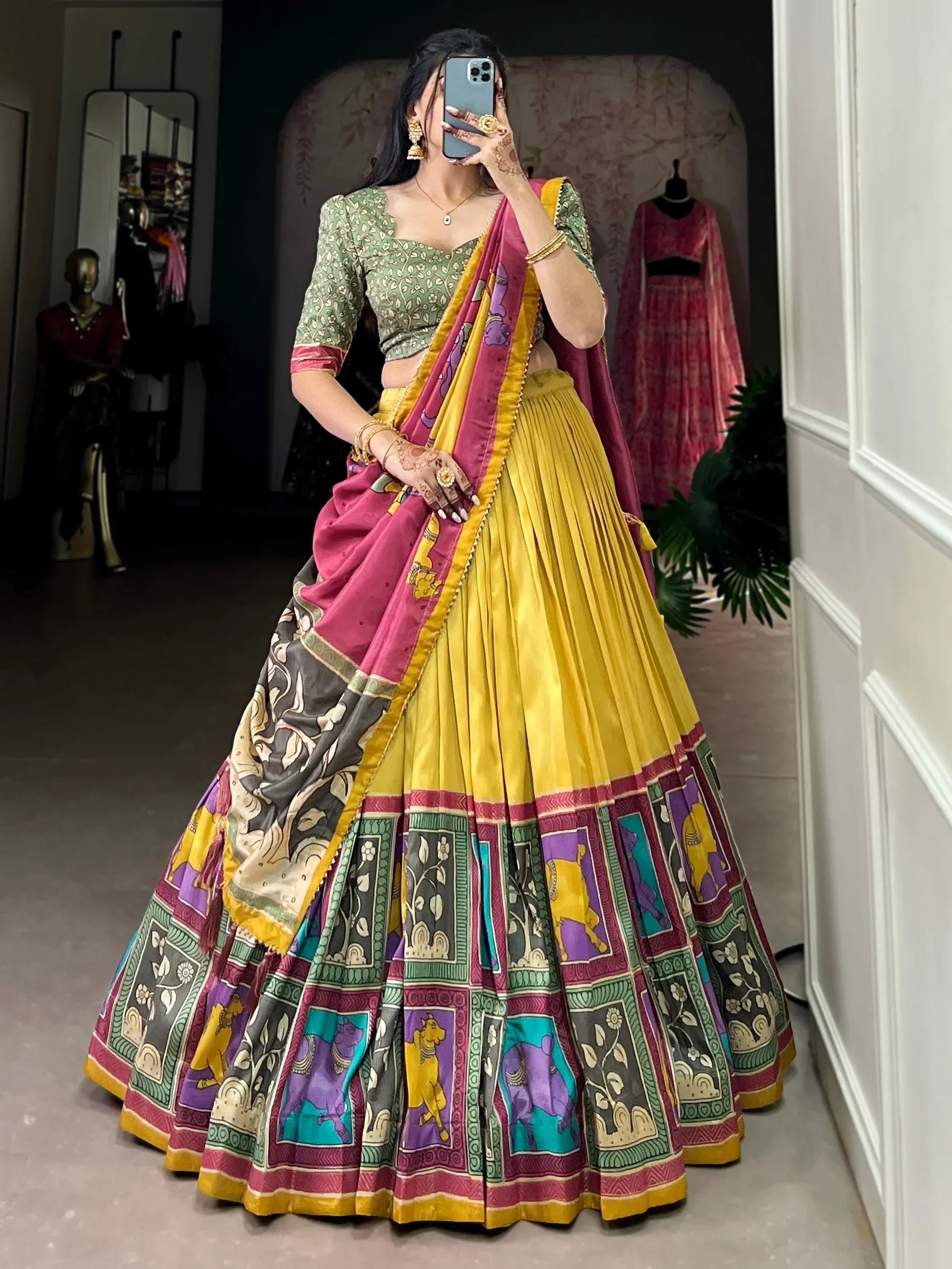 Woman in vibrant yellow and pink printed lehenga choli with floral blouse, perfect for Indian ethnic wear occasions.