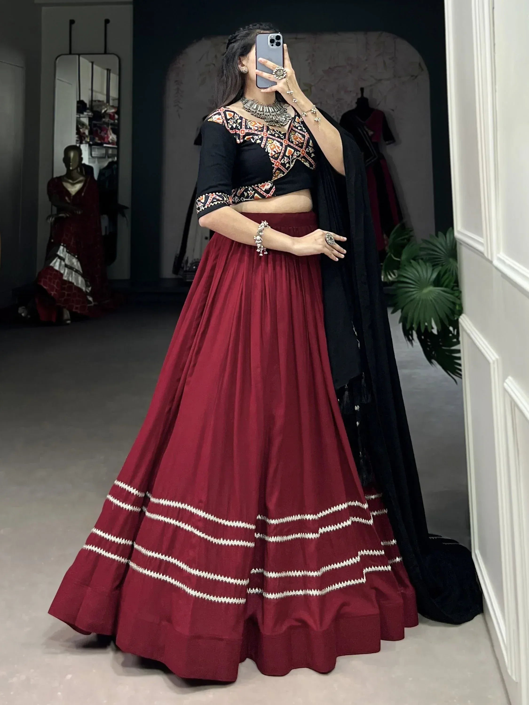 Woman in maroon lehenga with black embroidered blouse and dupatta, ethnic Indian wear