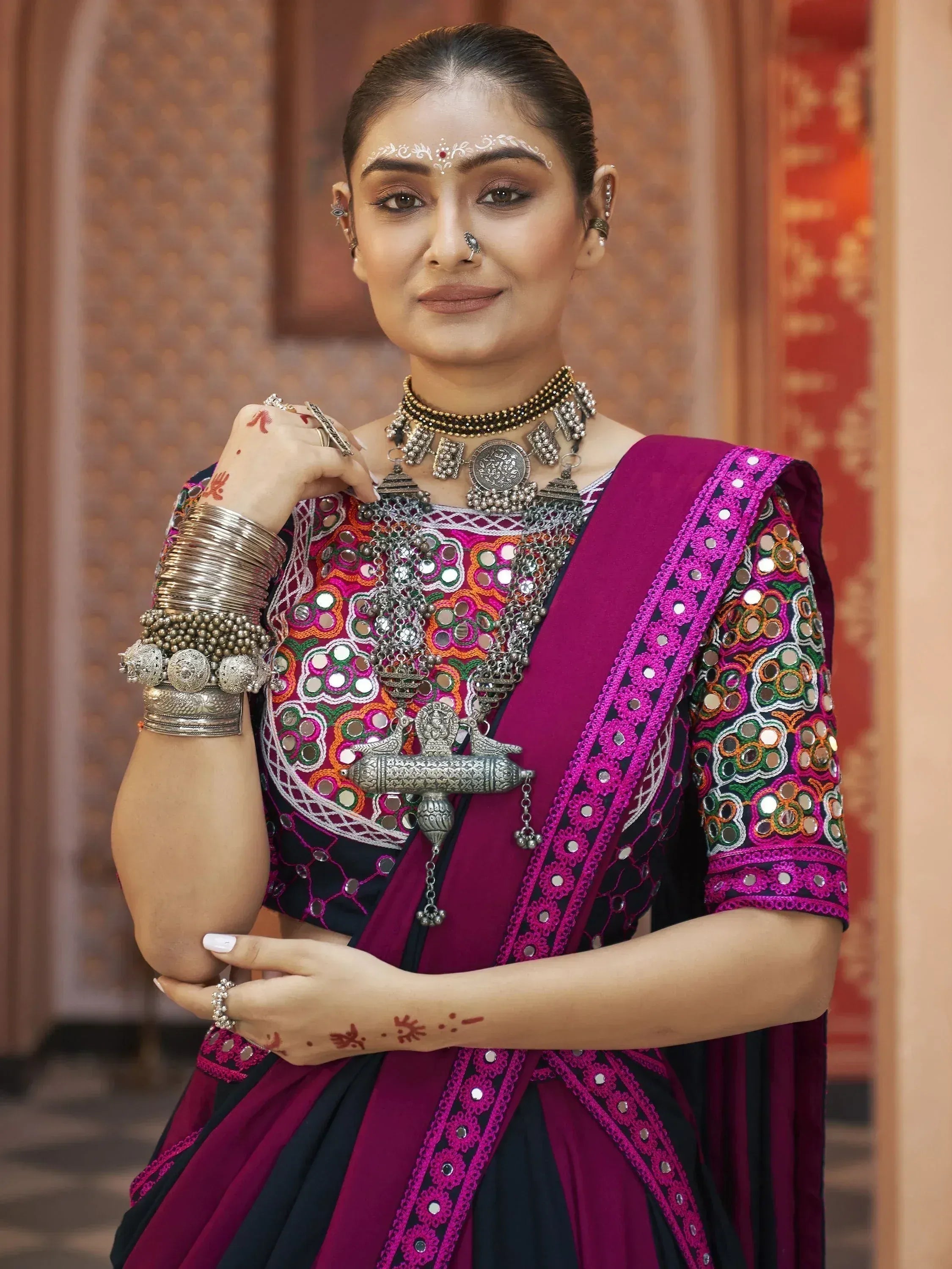 Woman in vibrant Indian ethnic wear with mirror work, traditional jewelry, and henna designs
