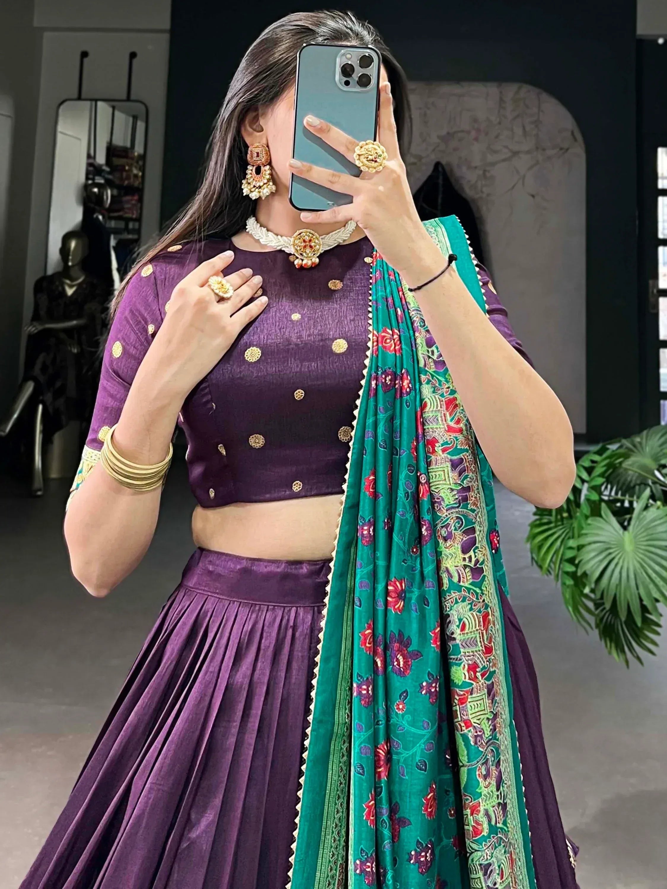 Purple lehenga choli with gold embroidery and green floral dupatta, styled with traditional jewelry