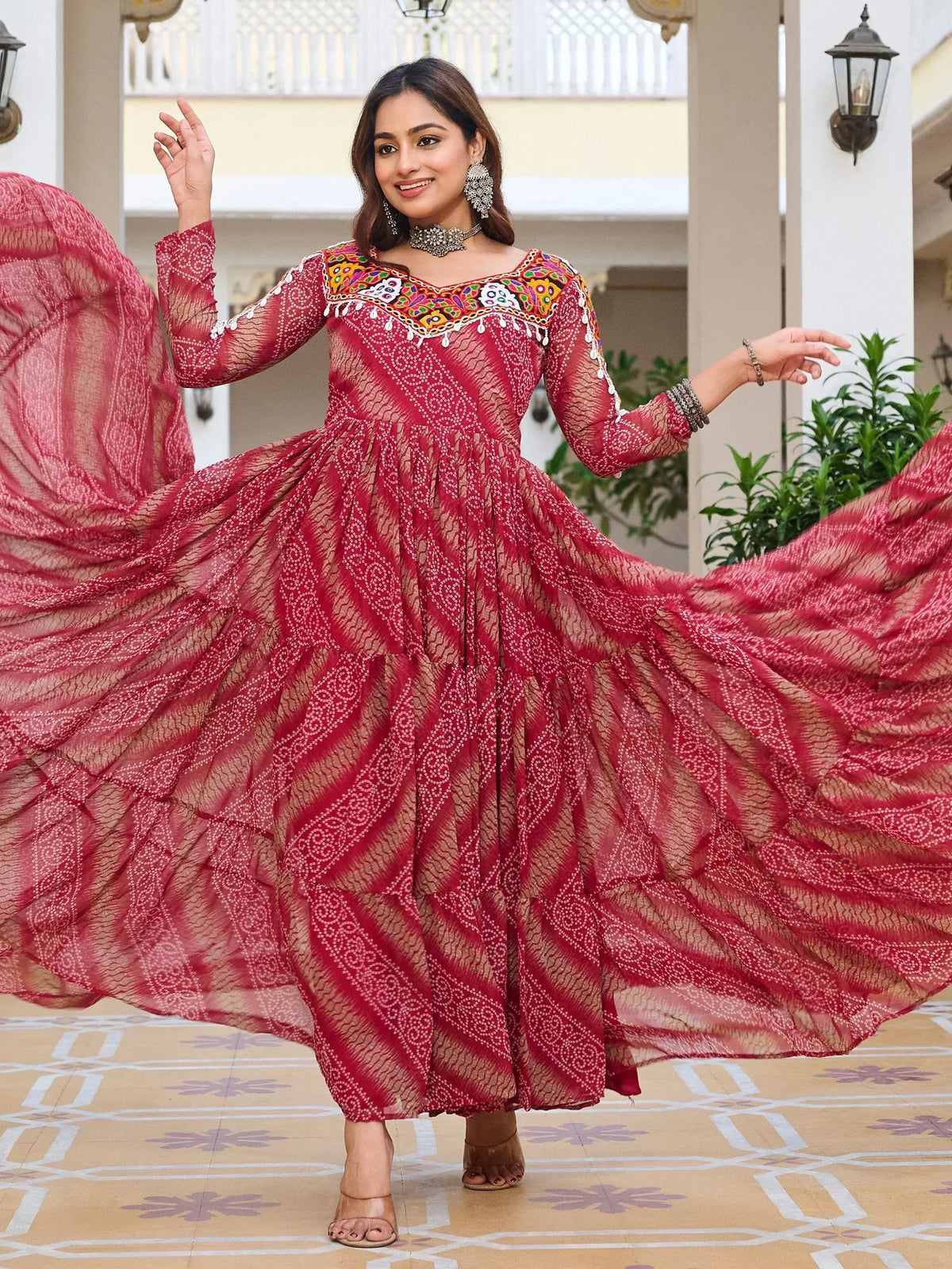 Woman twirling in red ethnic gown with mirror work, perfect for Indian festive occasions