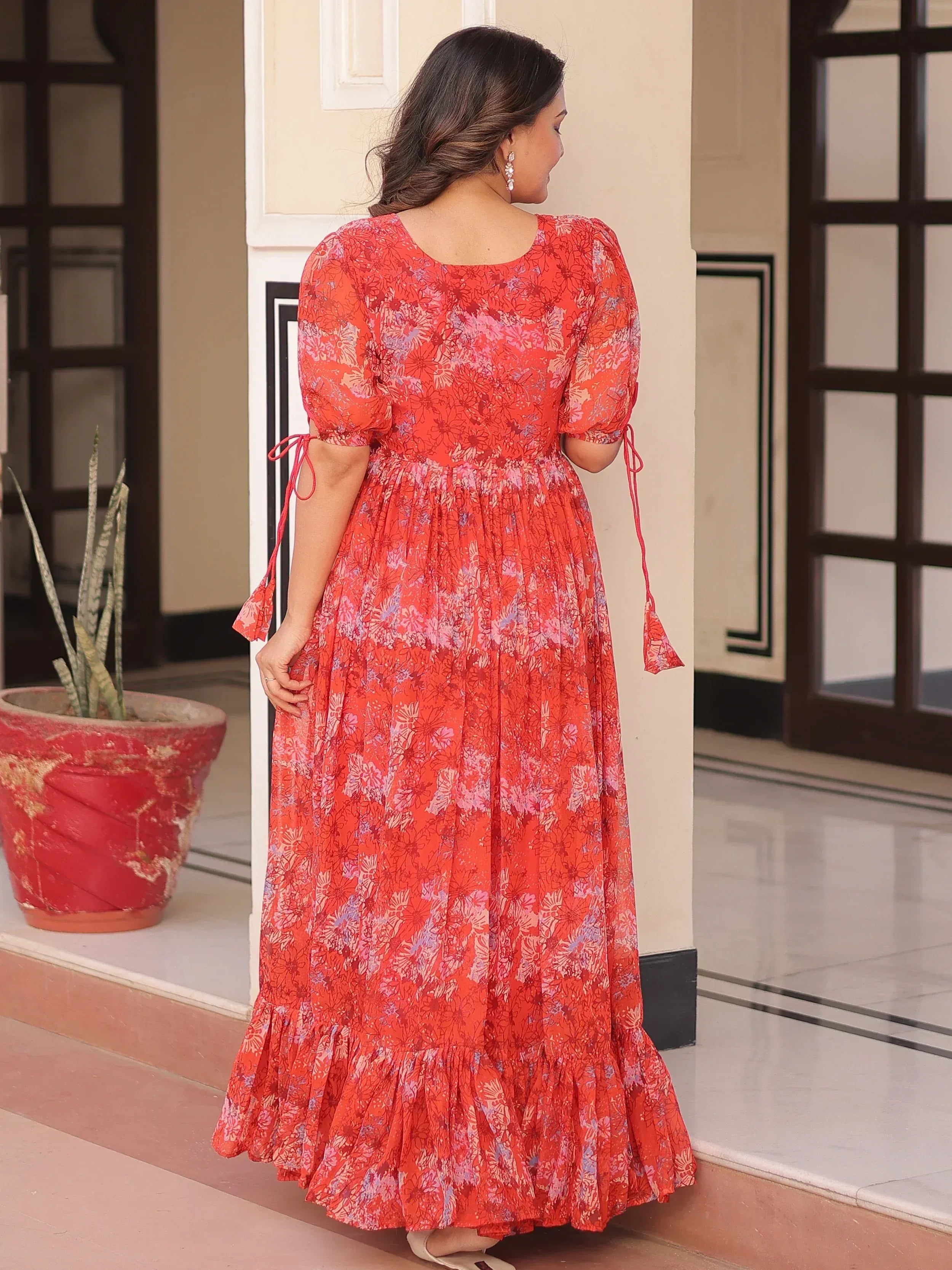 Red floral print ethnic gown with puff sleeves and tie-up details, perfect for Indian occasions.