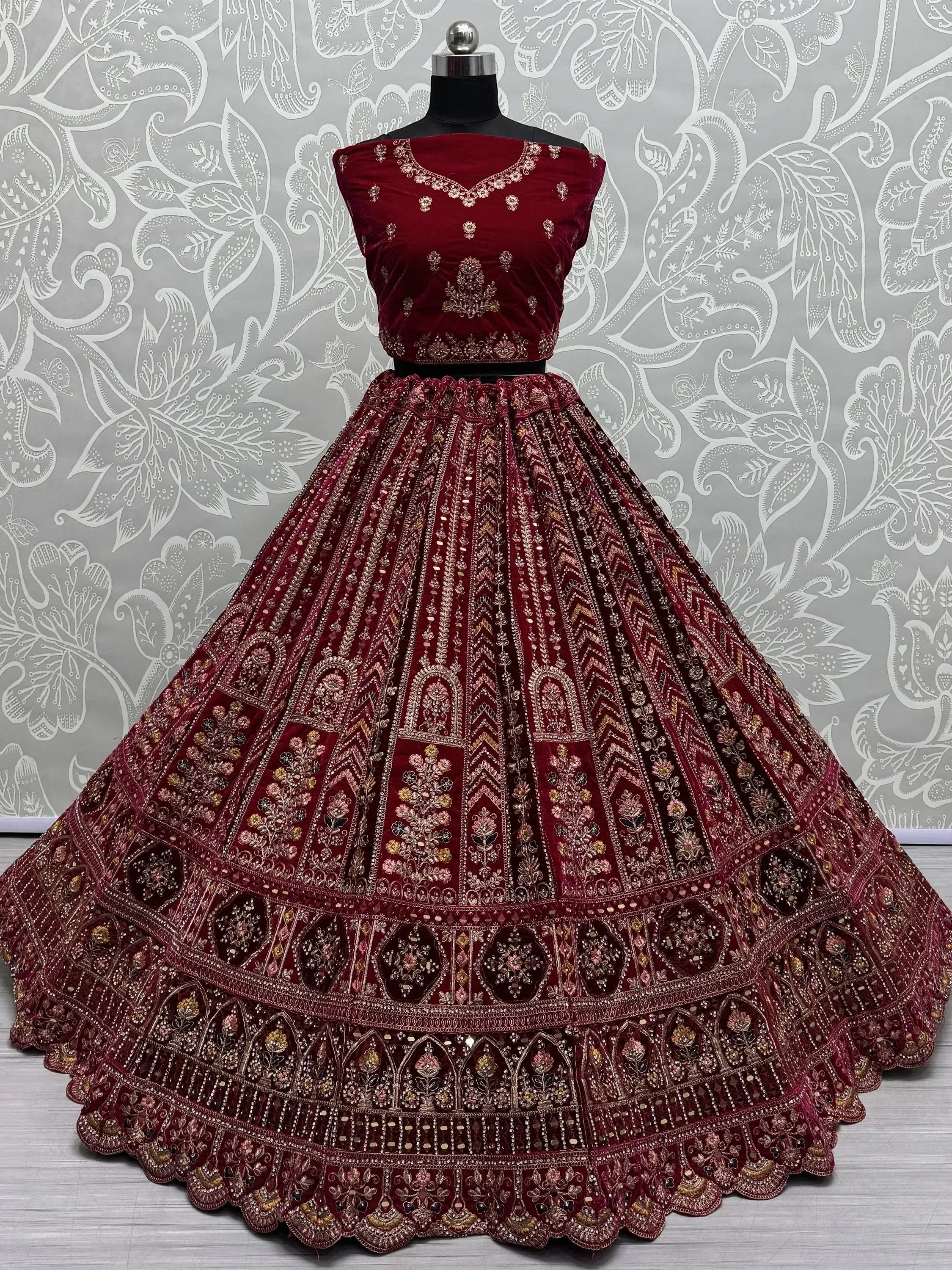 Maroon velvet lehenga choli with intricate gold embroidery and mirror work, perfect for Indian weddings and festive occasions.
