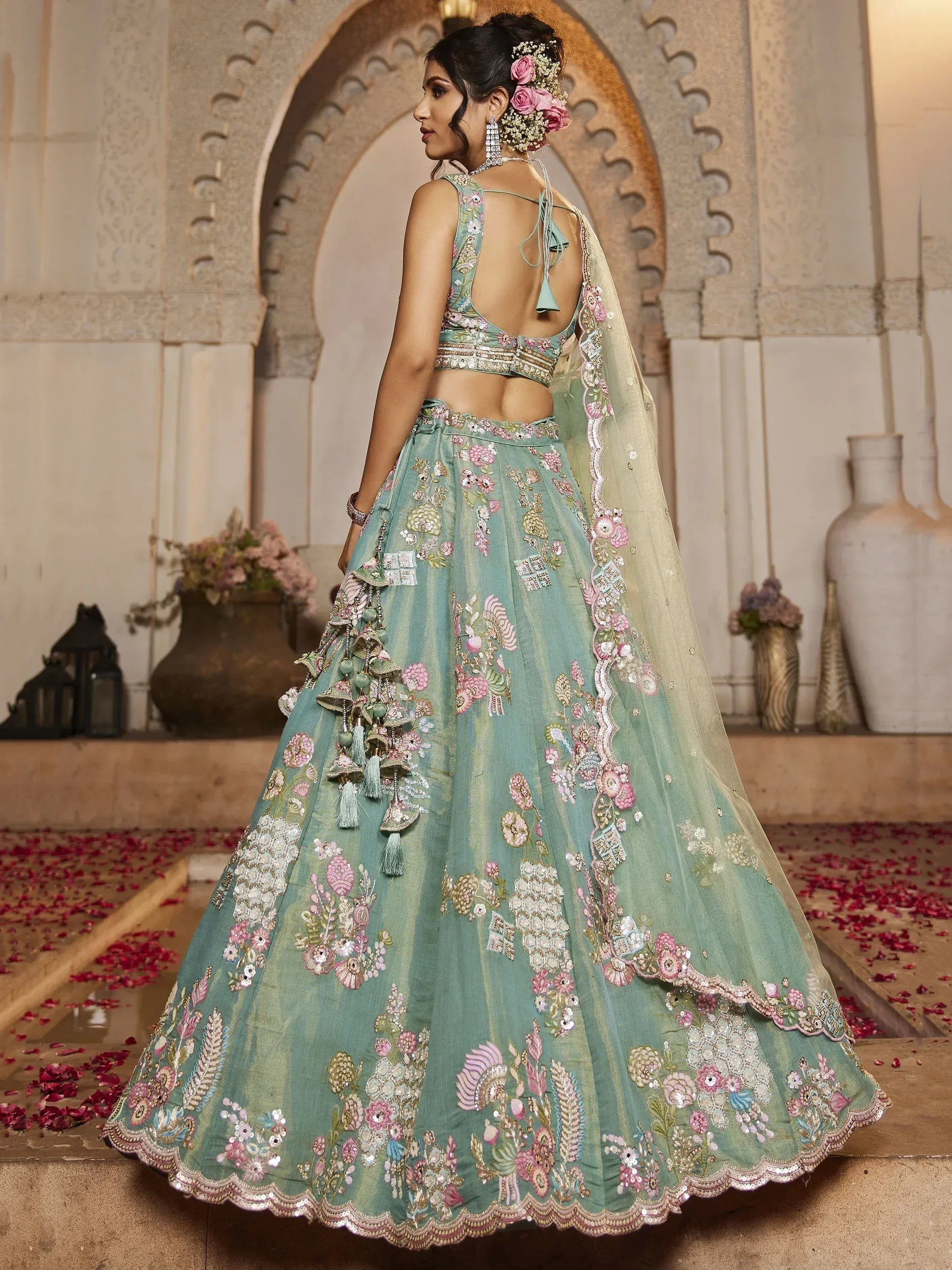 Mint green embroidered lehenga choli with floral motifs, tassels, and backless blouse for Indian weddings