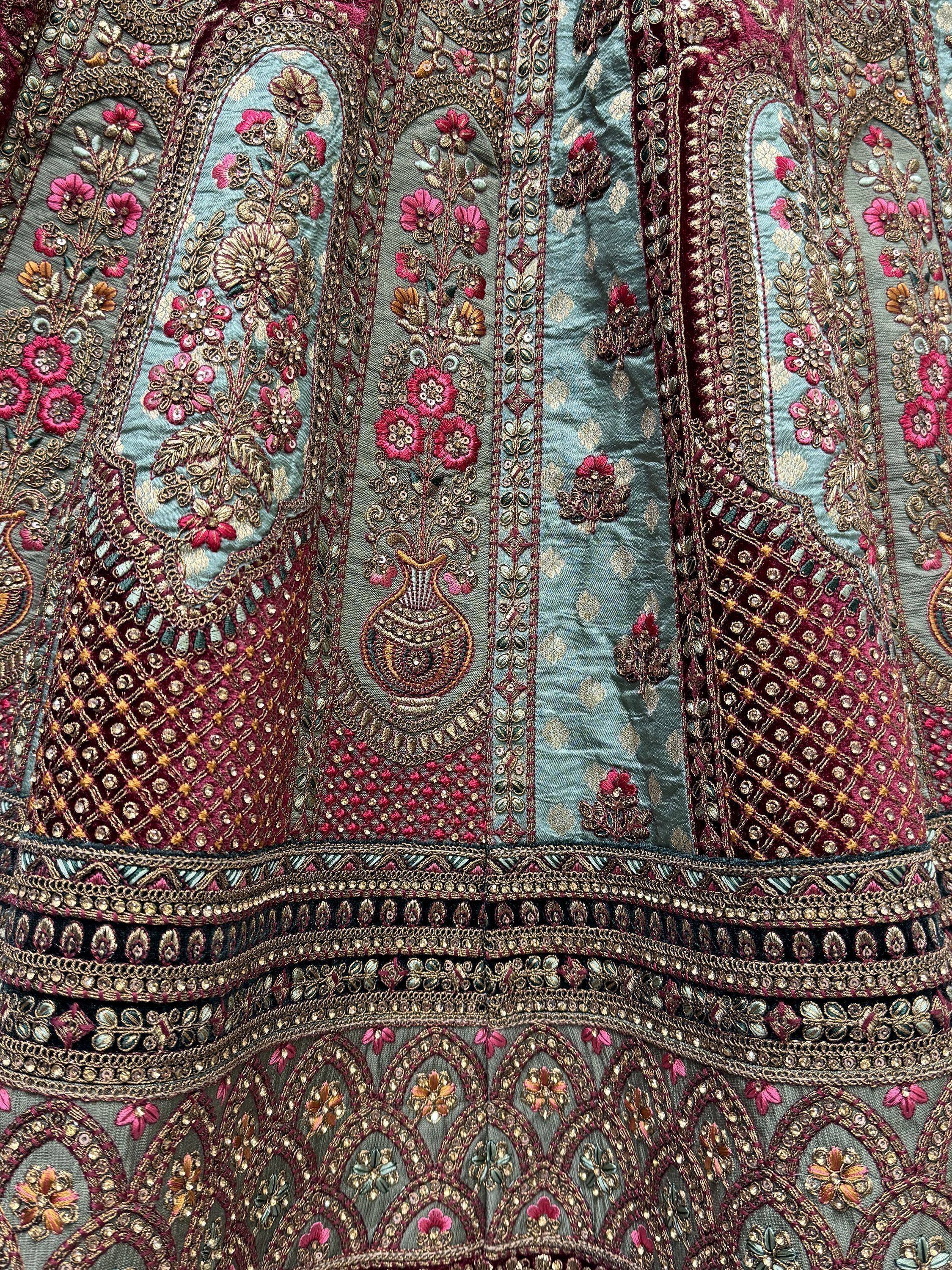 Exquisite Indian ethnic wear with intricate floral embroidery, sequins, and gold thread detailing on teal and maroon fabric.