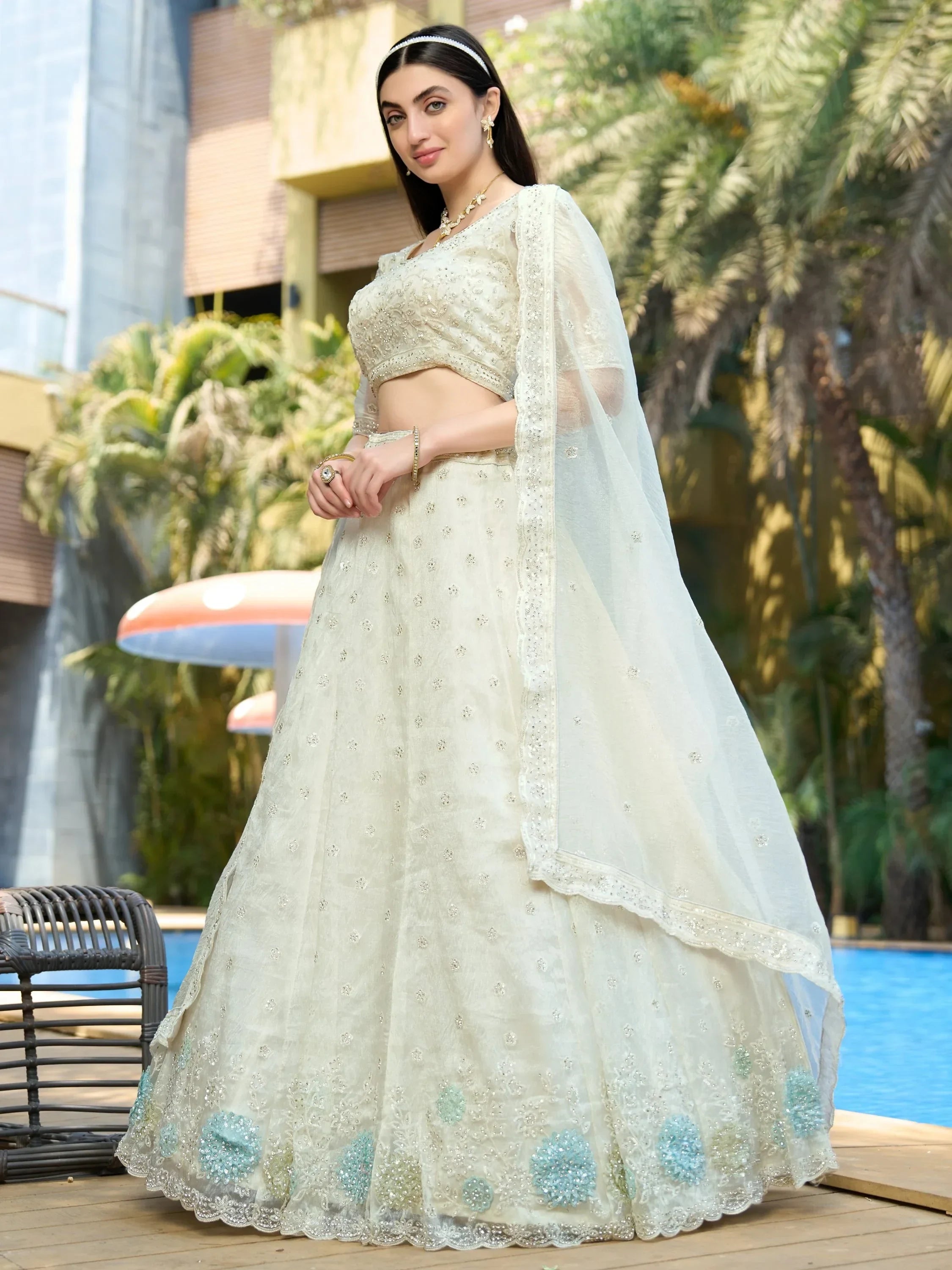Elegant ivory lehenga choli with blue floral embroidery, perfect for Indian weddings and festive occasions.