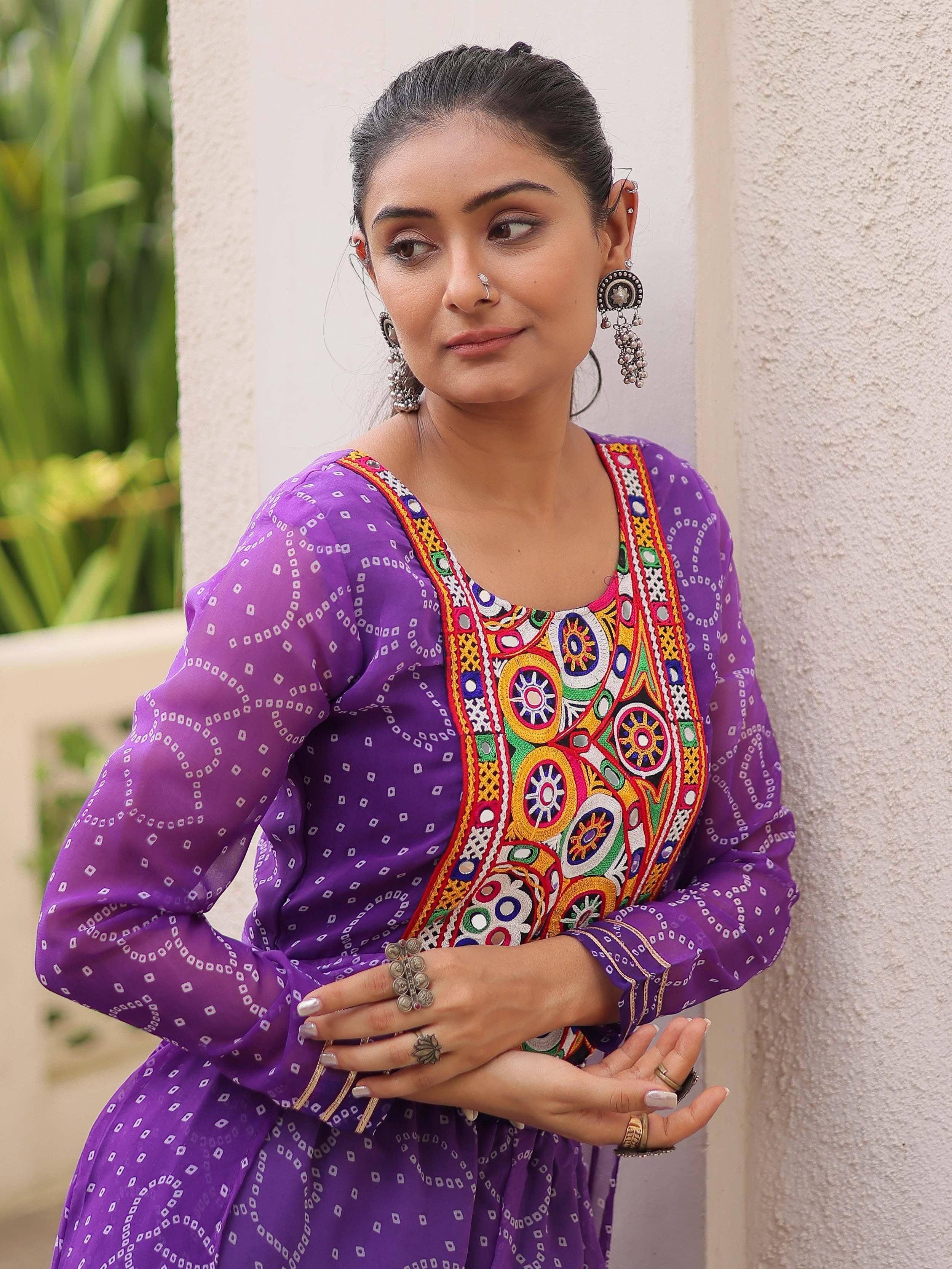 Purple ethnic kurti with colorful mirror embroidery, paired with traditional jewelry for festive wear