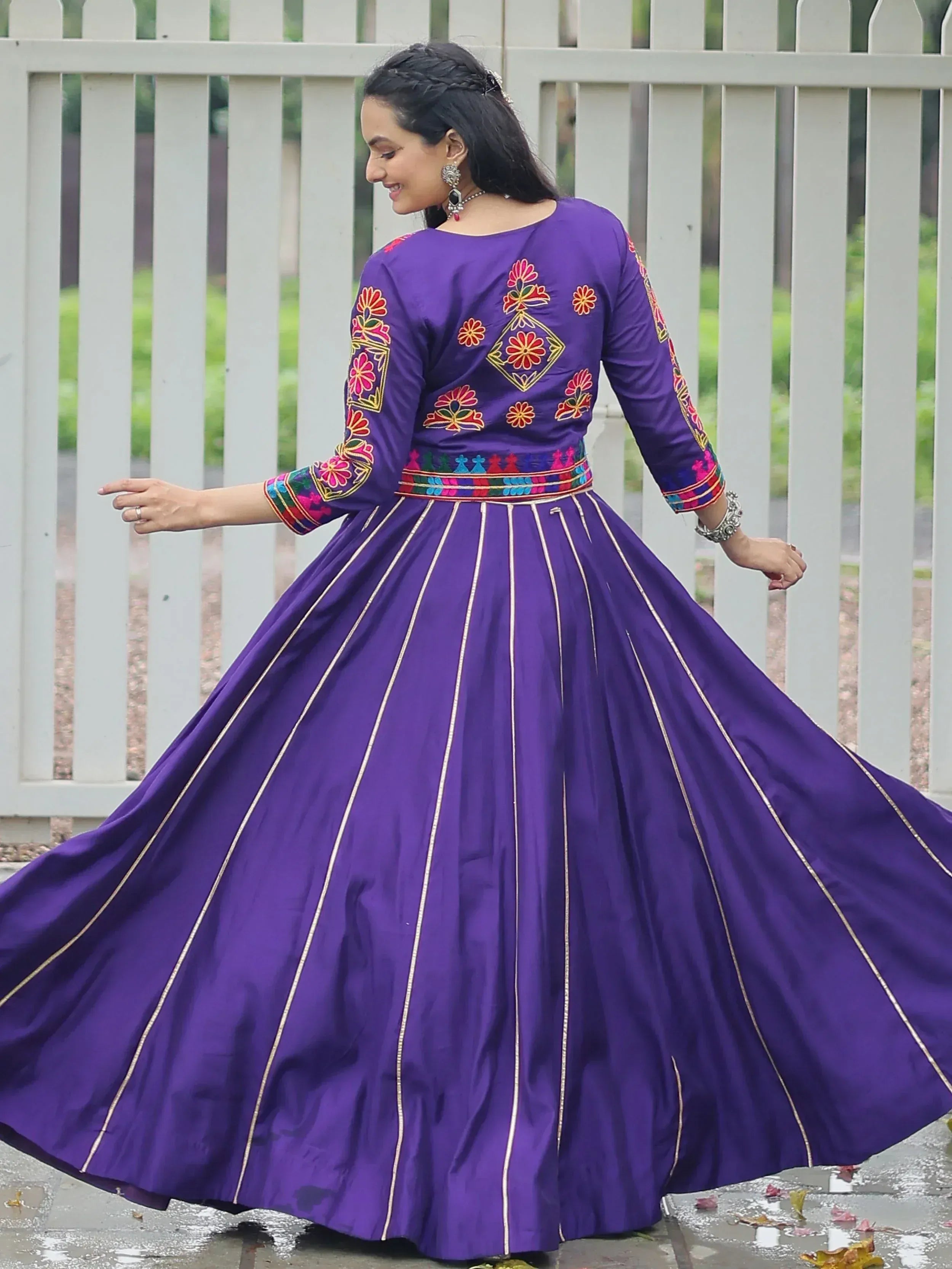Purple embroidered ethnic gown with floral motifs and gold stripes, perfect for Indian festive occasions.