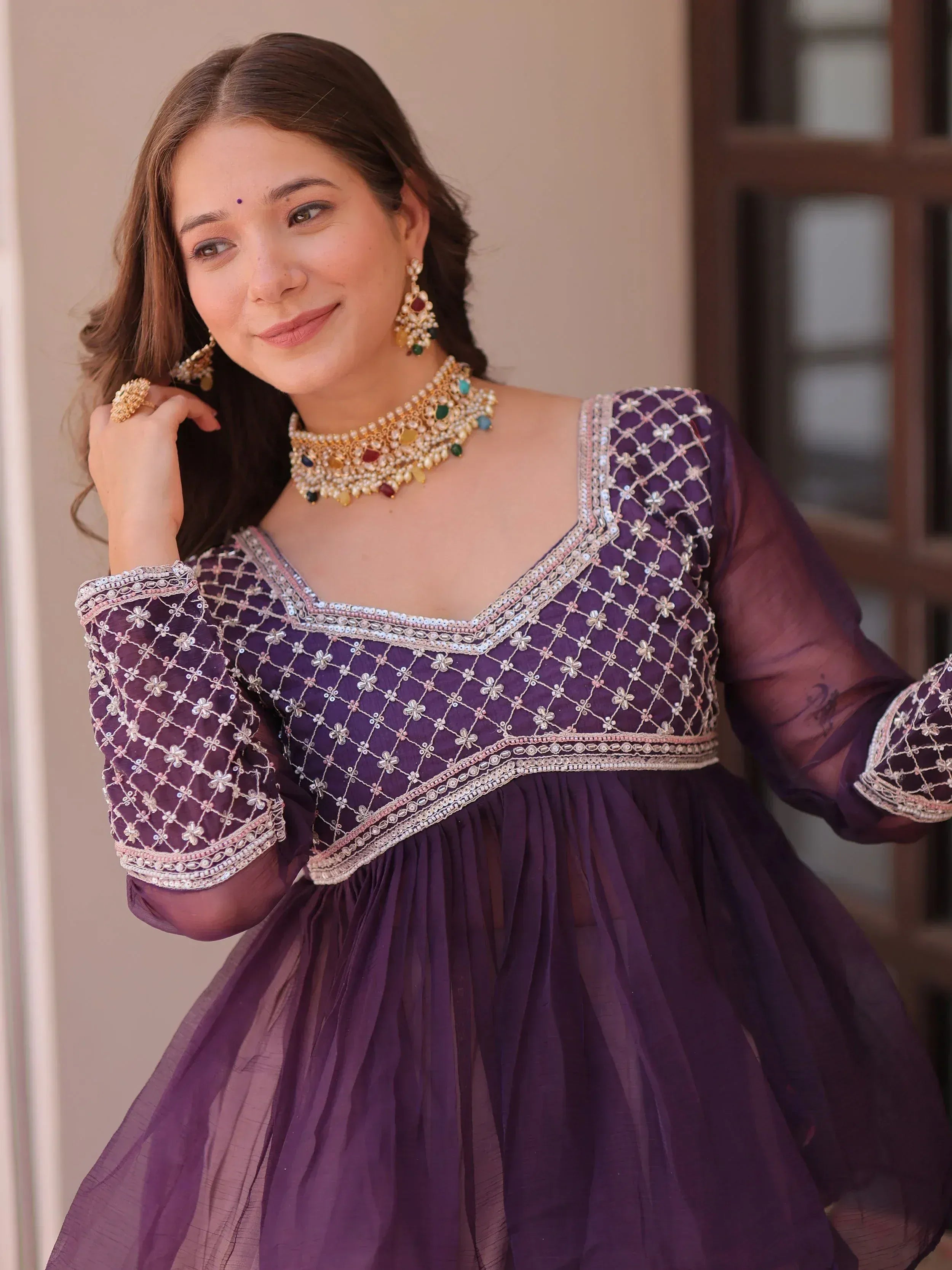 Purple ethnic gown with intricate embroidery and embellished neckline, paired with traditional jewelry