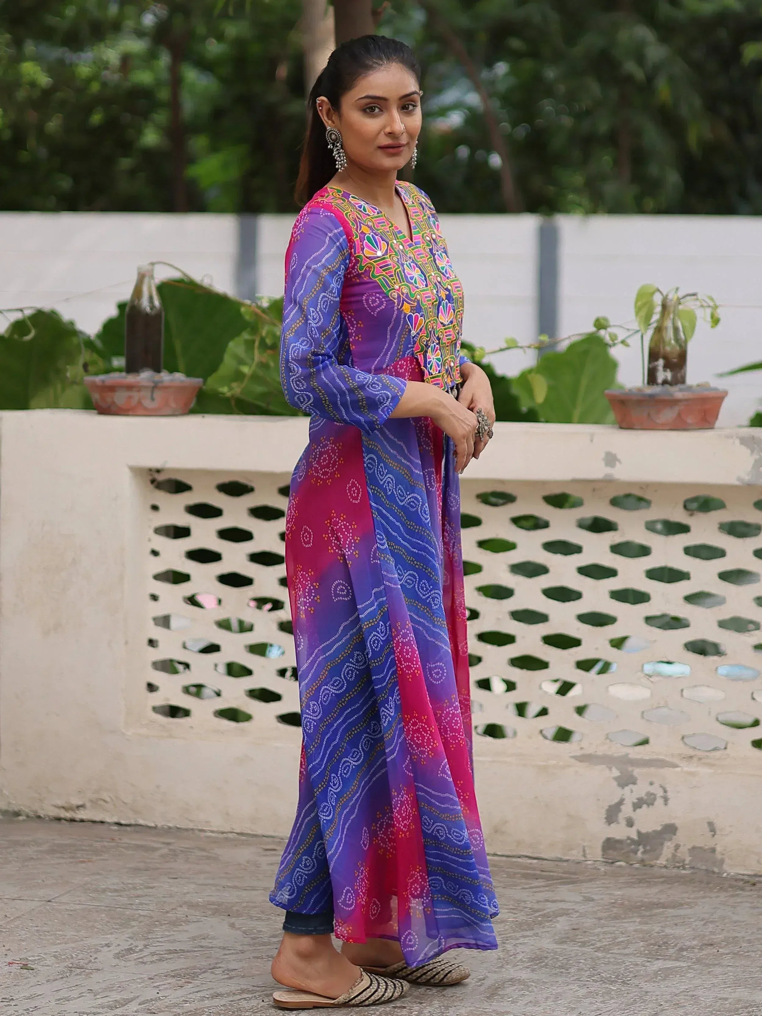 Woman in colorful embroidered ethnic gown with purple and pink hues, perfect for Indian festive wear