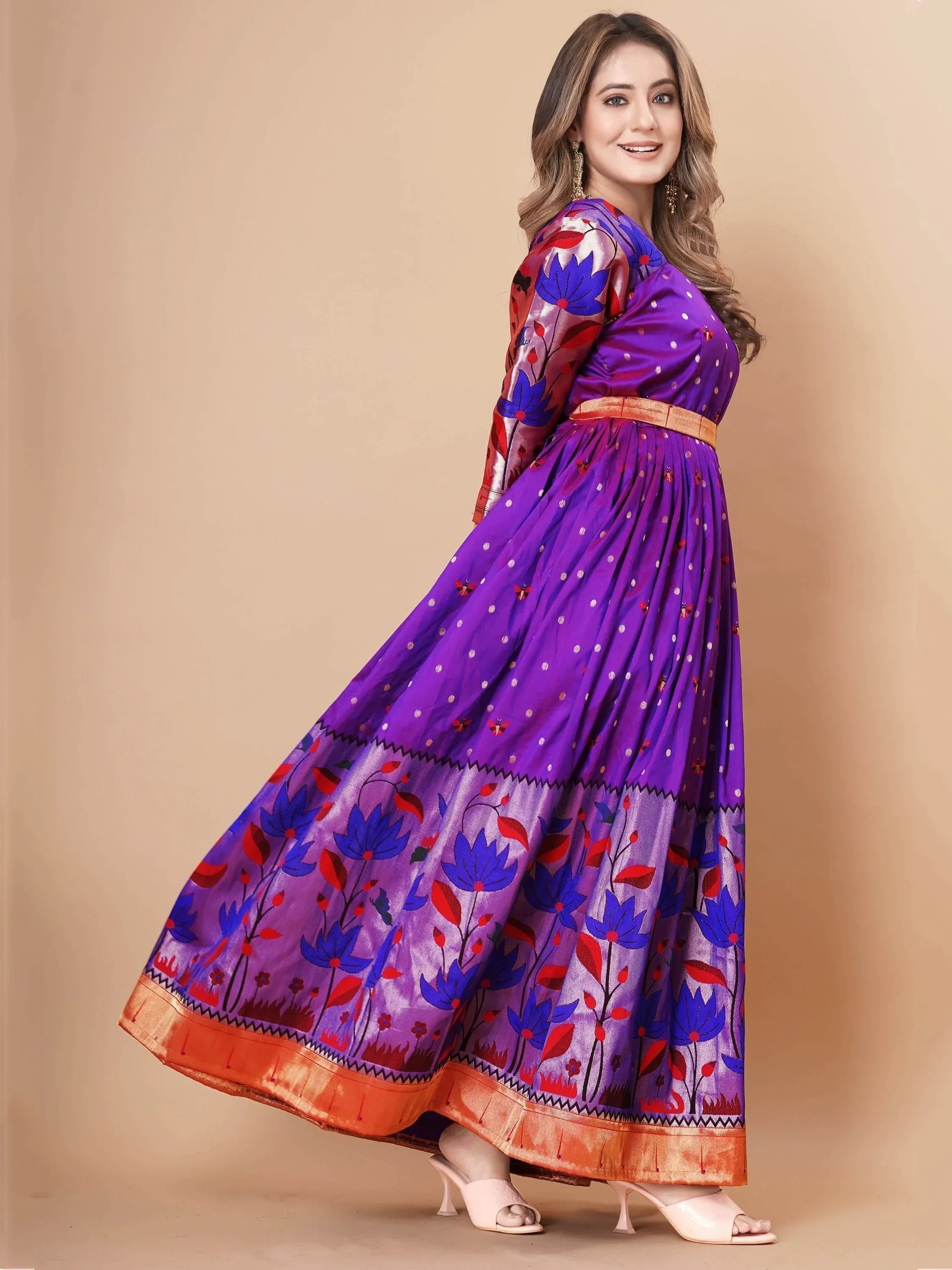 Woman in purple ethnic gown with floral print and gold border, posing in studio