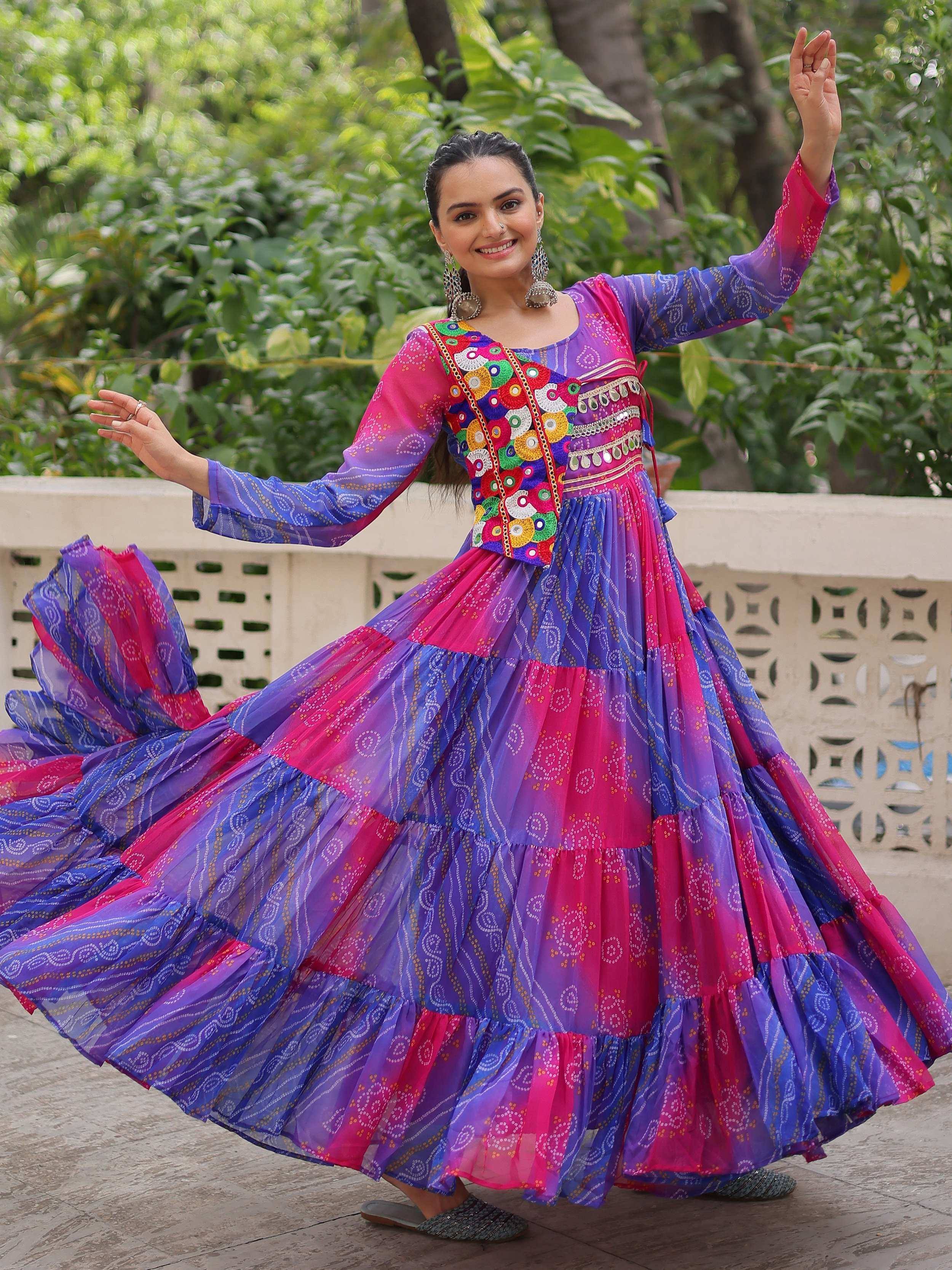 Woman in vibrant purple and pink ethnic gown with mirror work, twirling outdoors