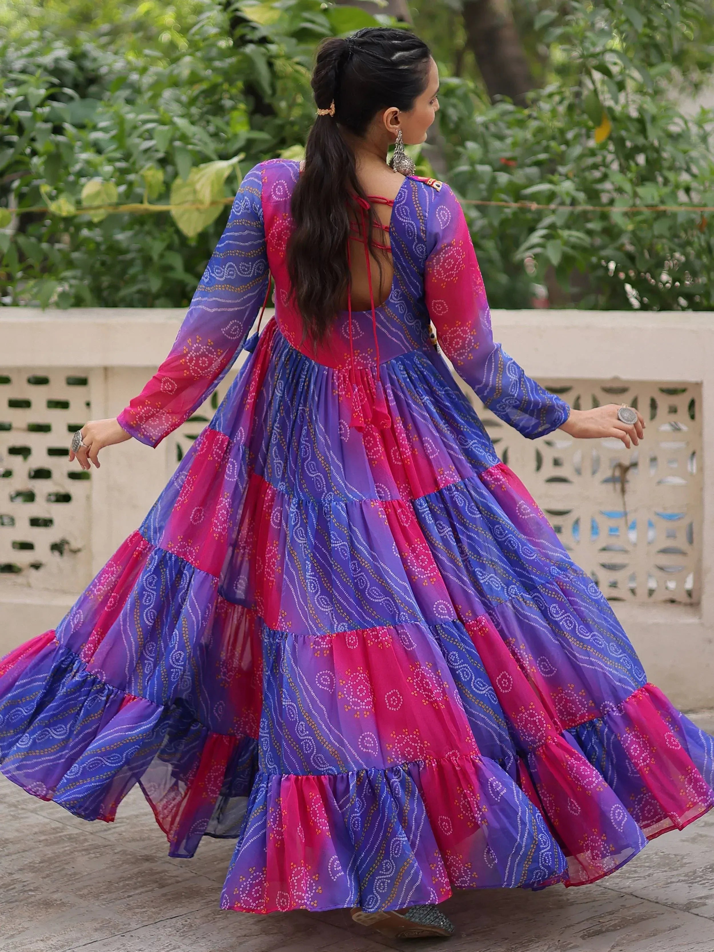 Woman in vibrant purple and pink tiered ethnic gown with back tie detail, perfect for festive occasions.