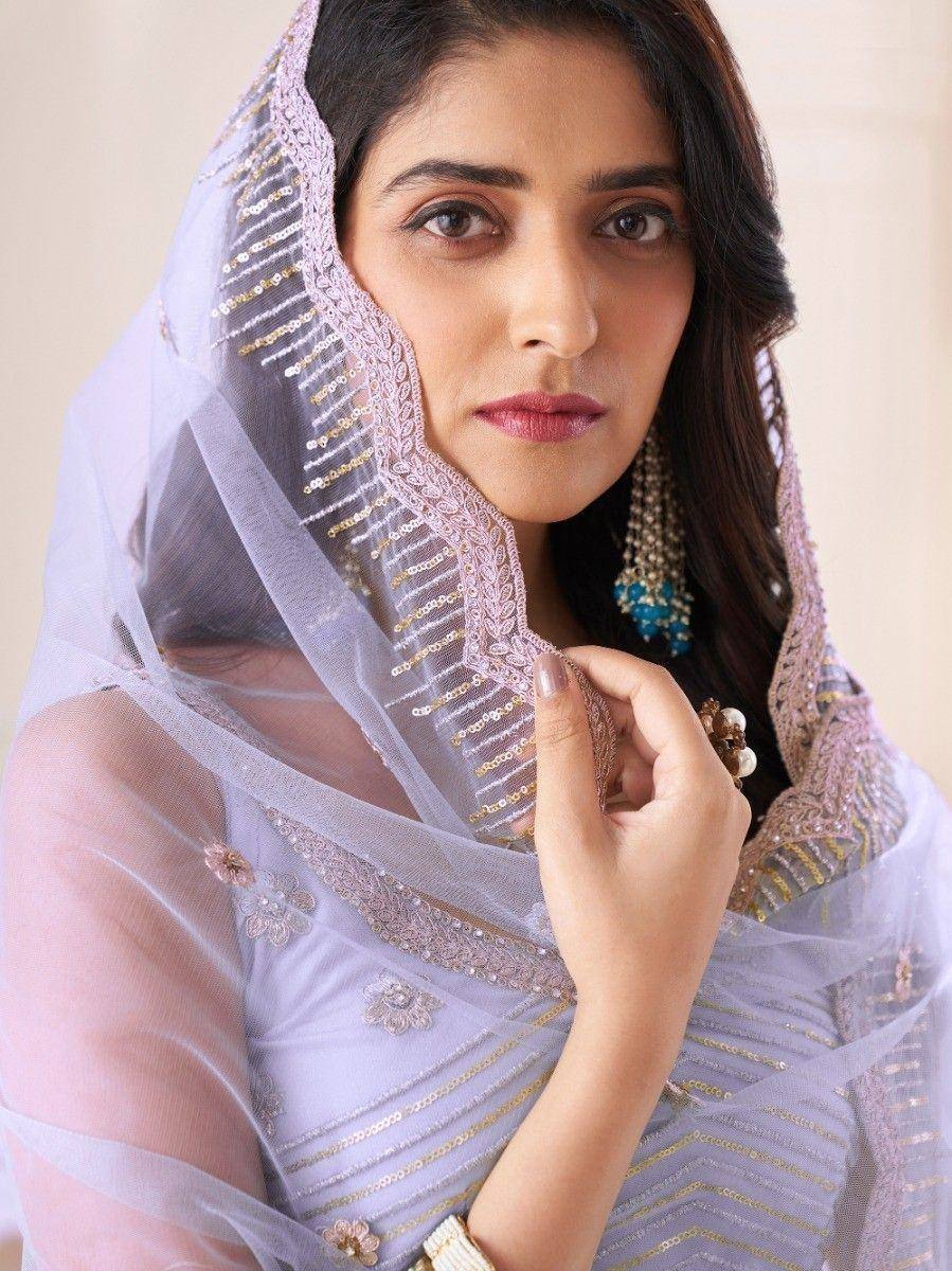 Elegant lavender saree with gold embroidery and sheer dupatta, styled with statement earrings for Indian ethnic wear.