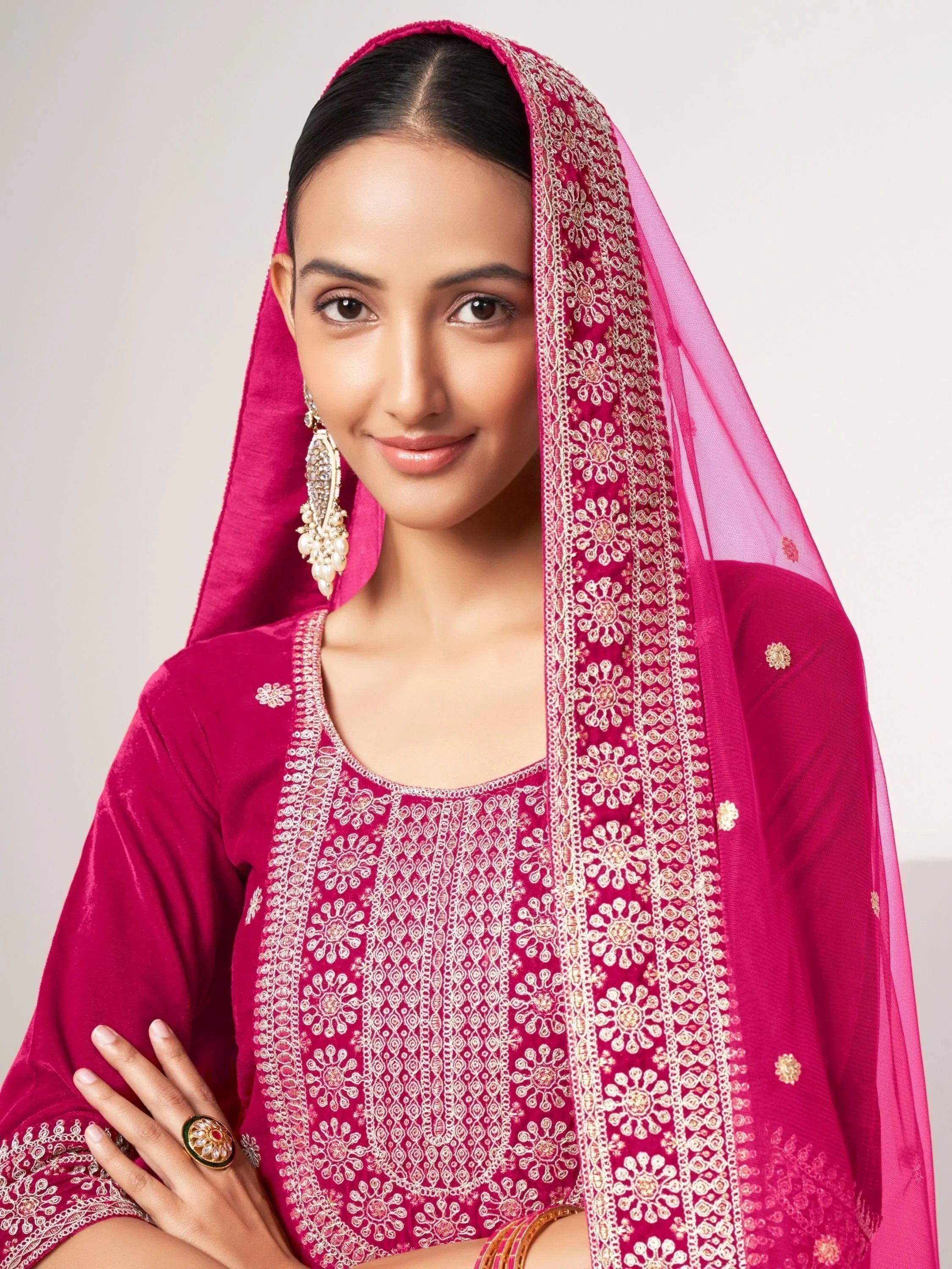 Woman in pink embroidered ethnic salwar kameez with matching dupatta and traditional jewelry