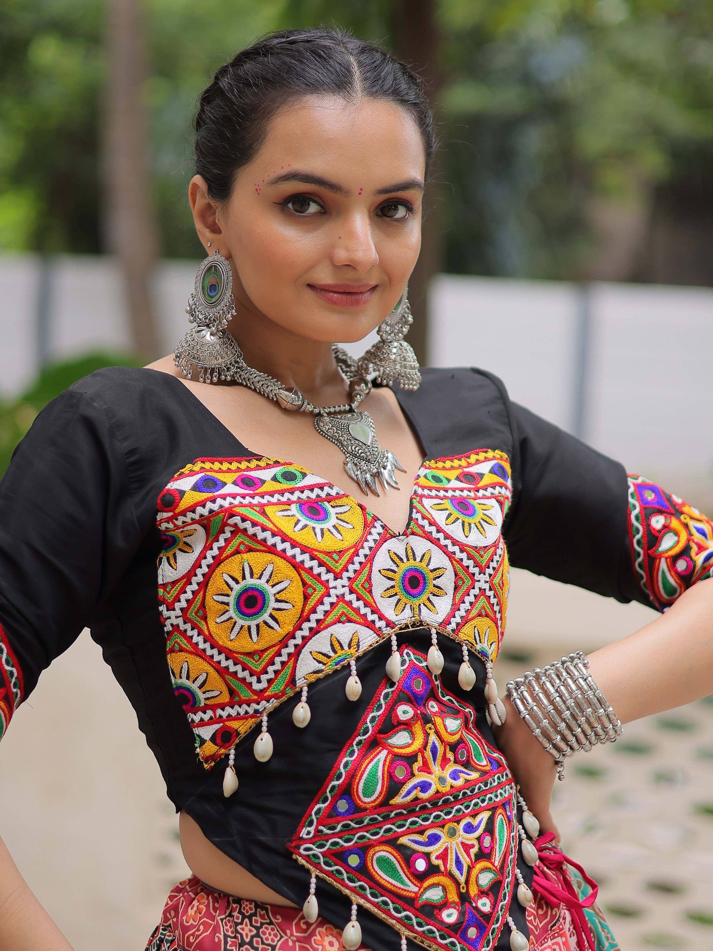 Woman in black embroidered ethnic top with colorful mirror work, silver jewelry, and traditional Indian attire