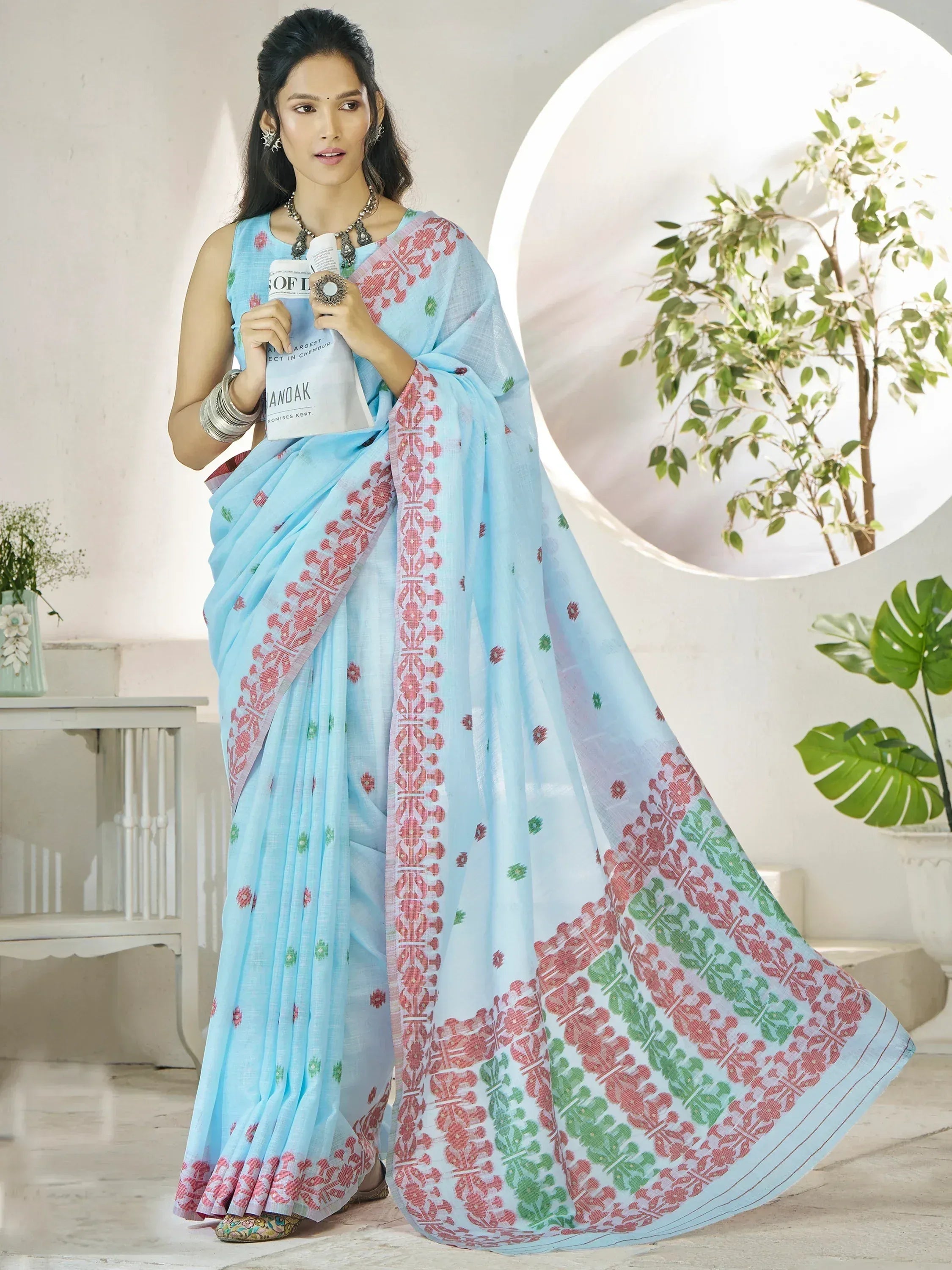 Light blue saree with red and green block print patterns, styled with ethnic jewelry for traditional Indian wear.