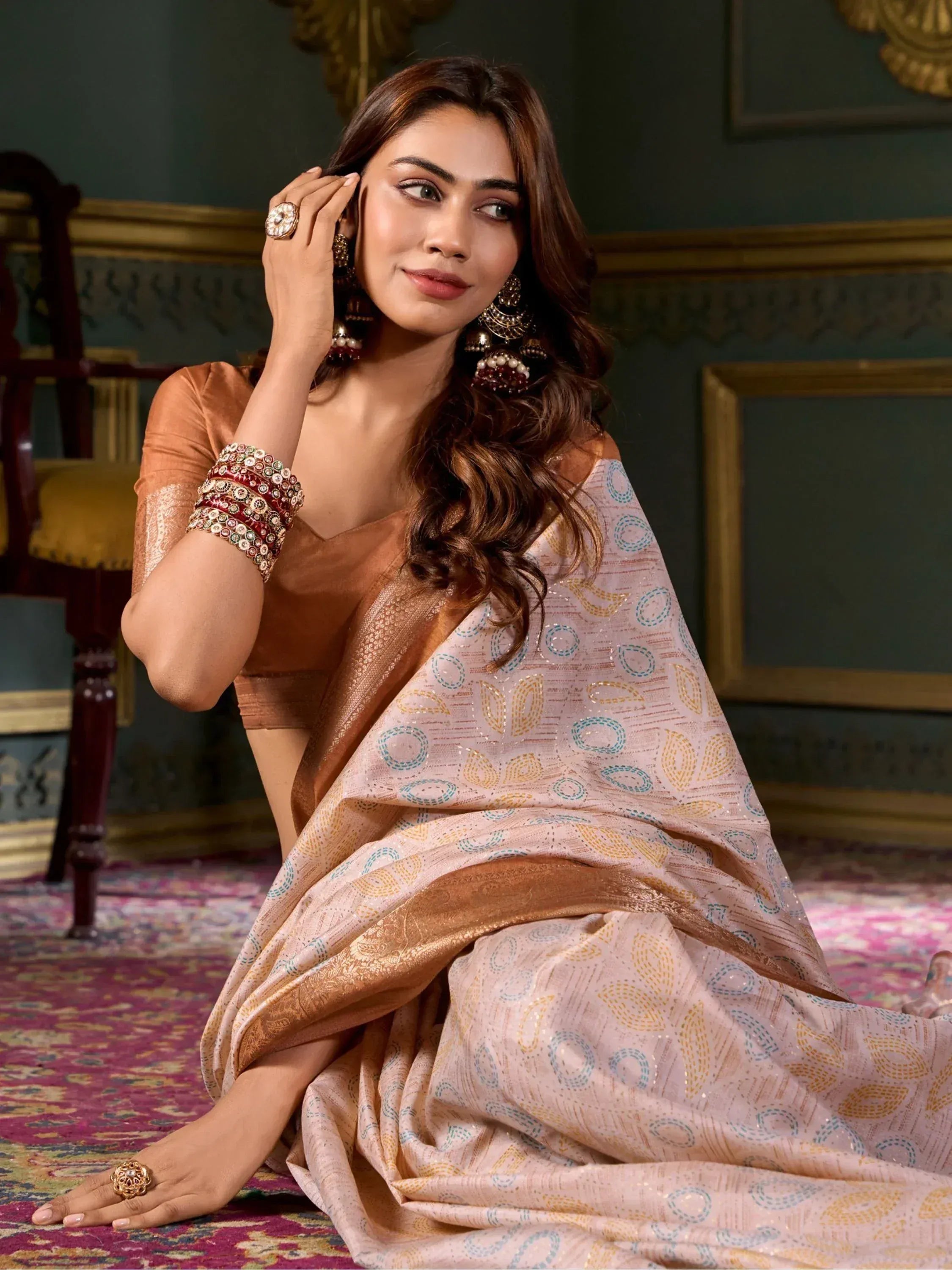 Woman in elegant Indian saree with gold and blue motifs, paired with traditional jewelry and blouse