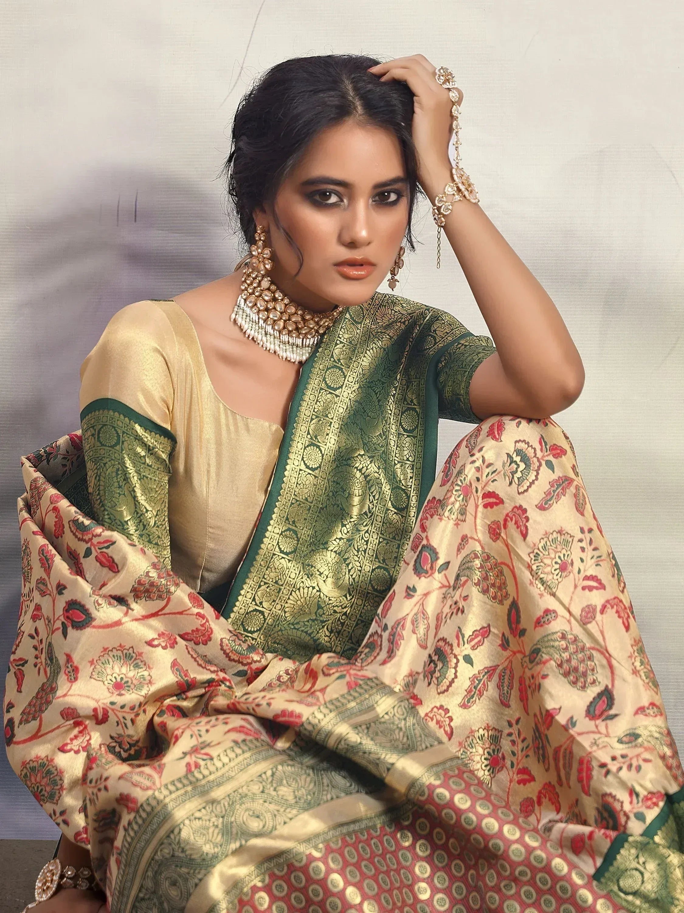 Woman in elegant Indian saree with gold and green floral print, paired with traditional jewelry for festive occasions
