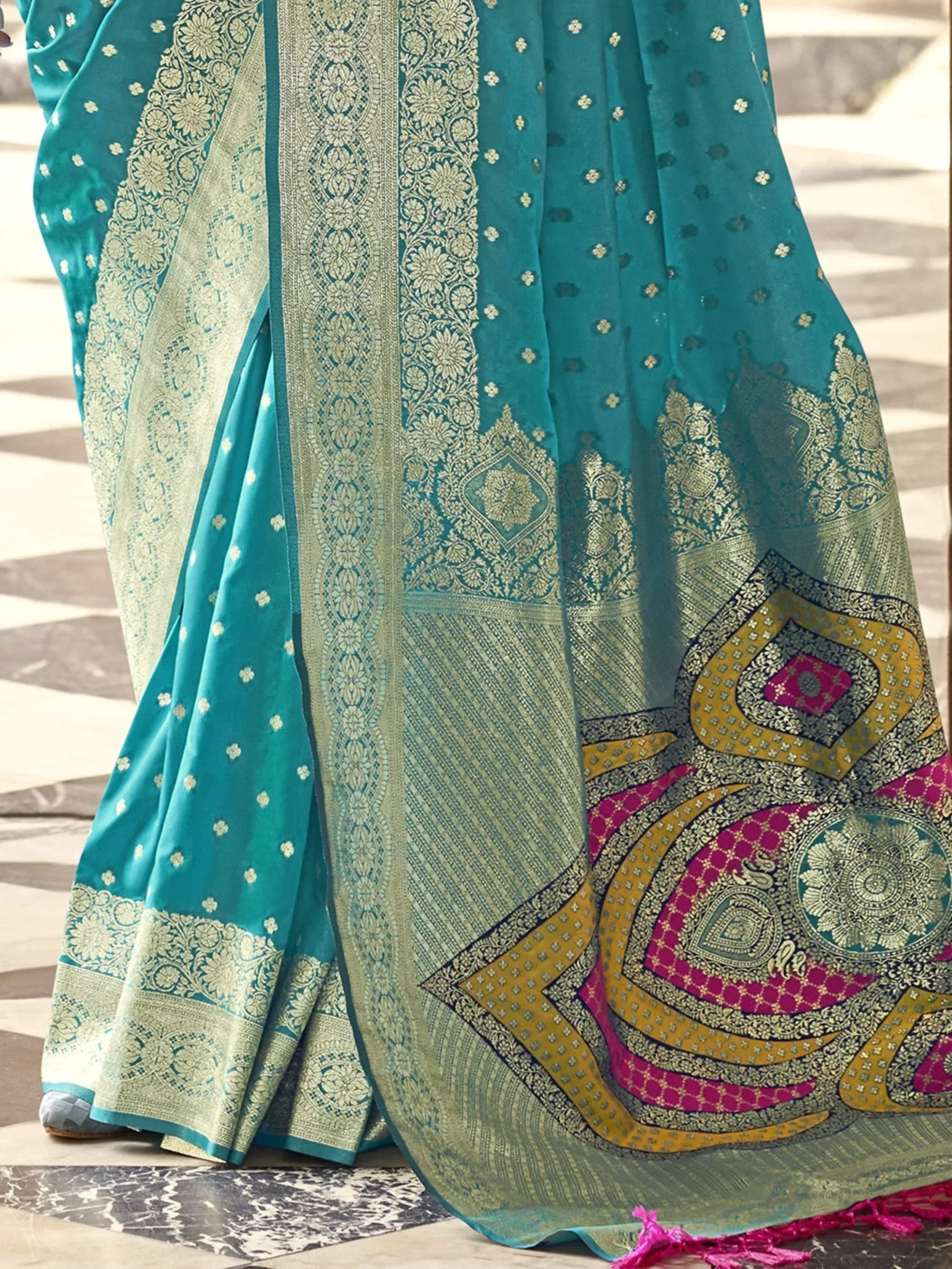 Teal designer saree with gold zari, floral motifs, and vibrant pink-gold border for ethnic wear