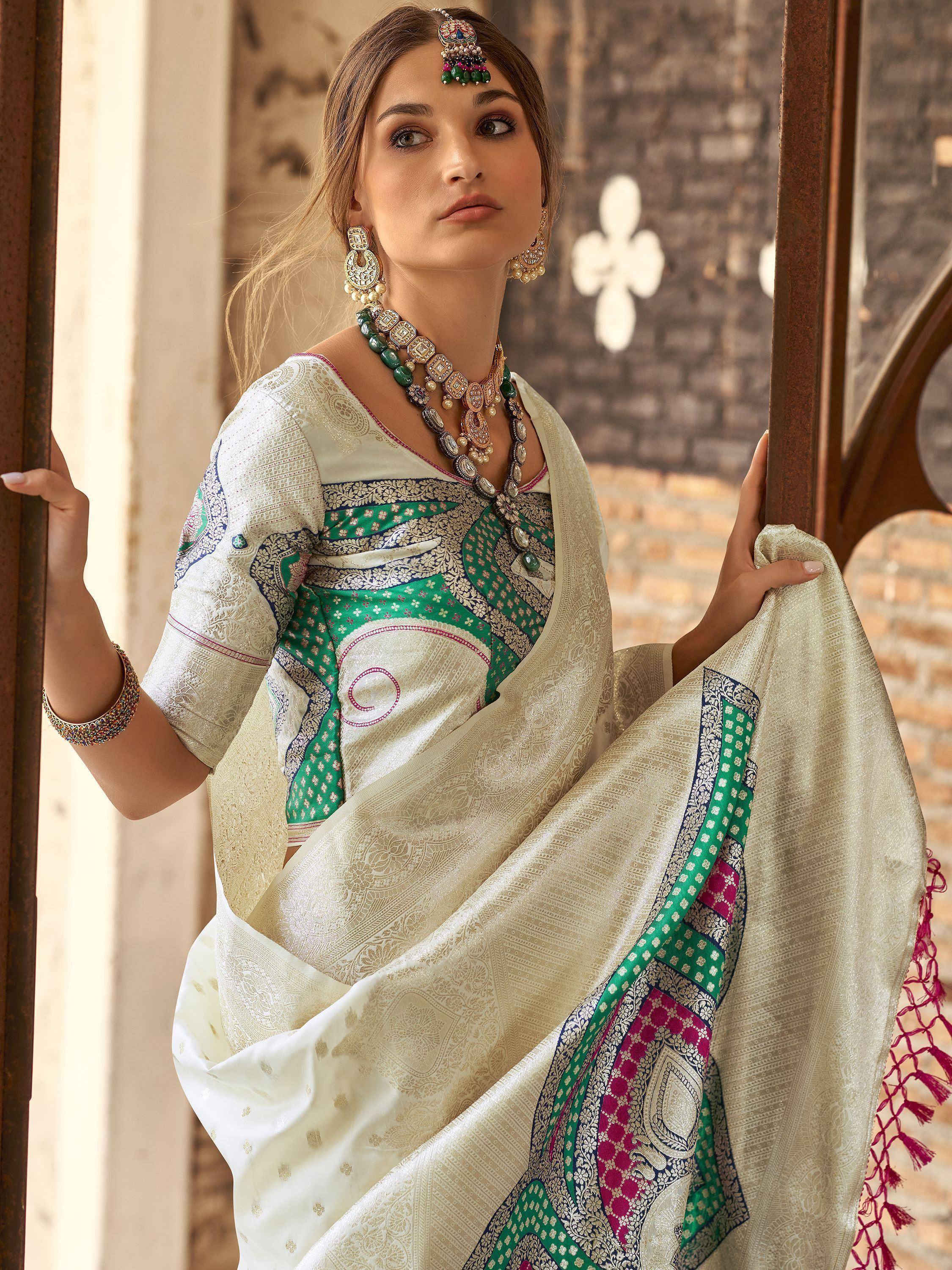 Elegant cream saree with green and pink embroidery, paired with traditional Indian jewelry for festive occasions