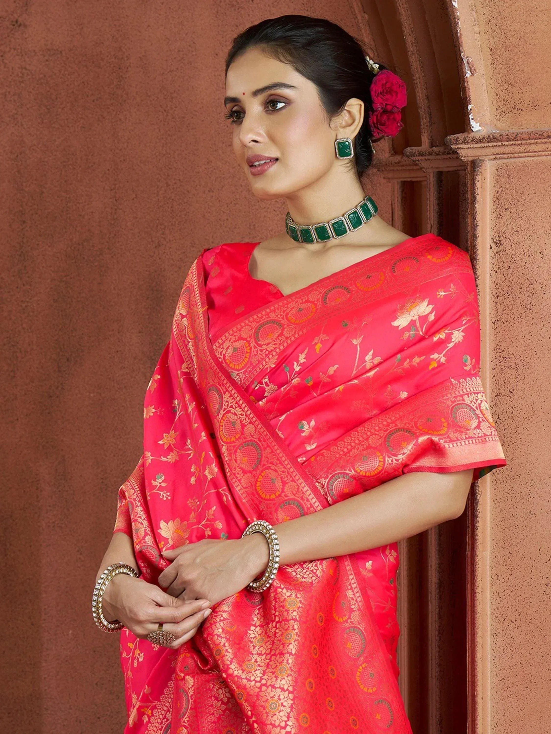 Woman in vibrant pink designer saree with gold floral embroidery, paired with green jewelry, perfect for Indian ethnic occasions.