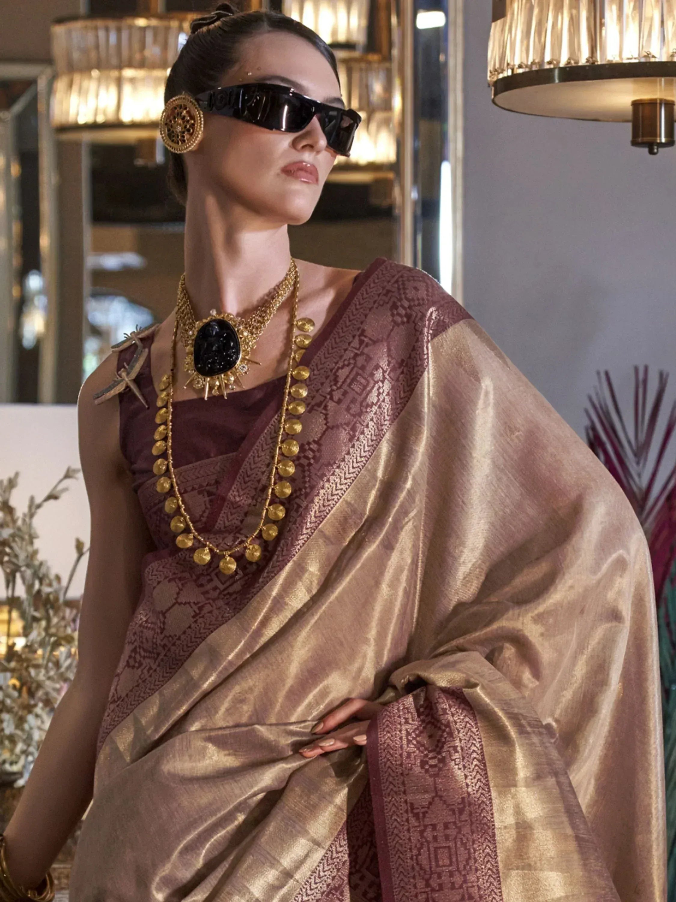 Woman in maroon and gold ethnic saree with designer jewelry and sunglasses