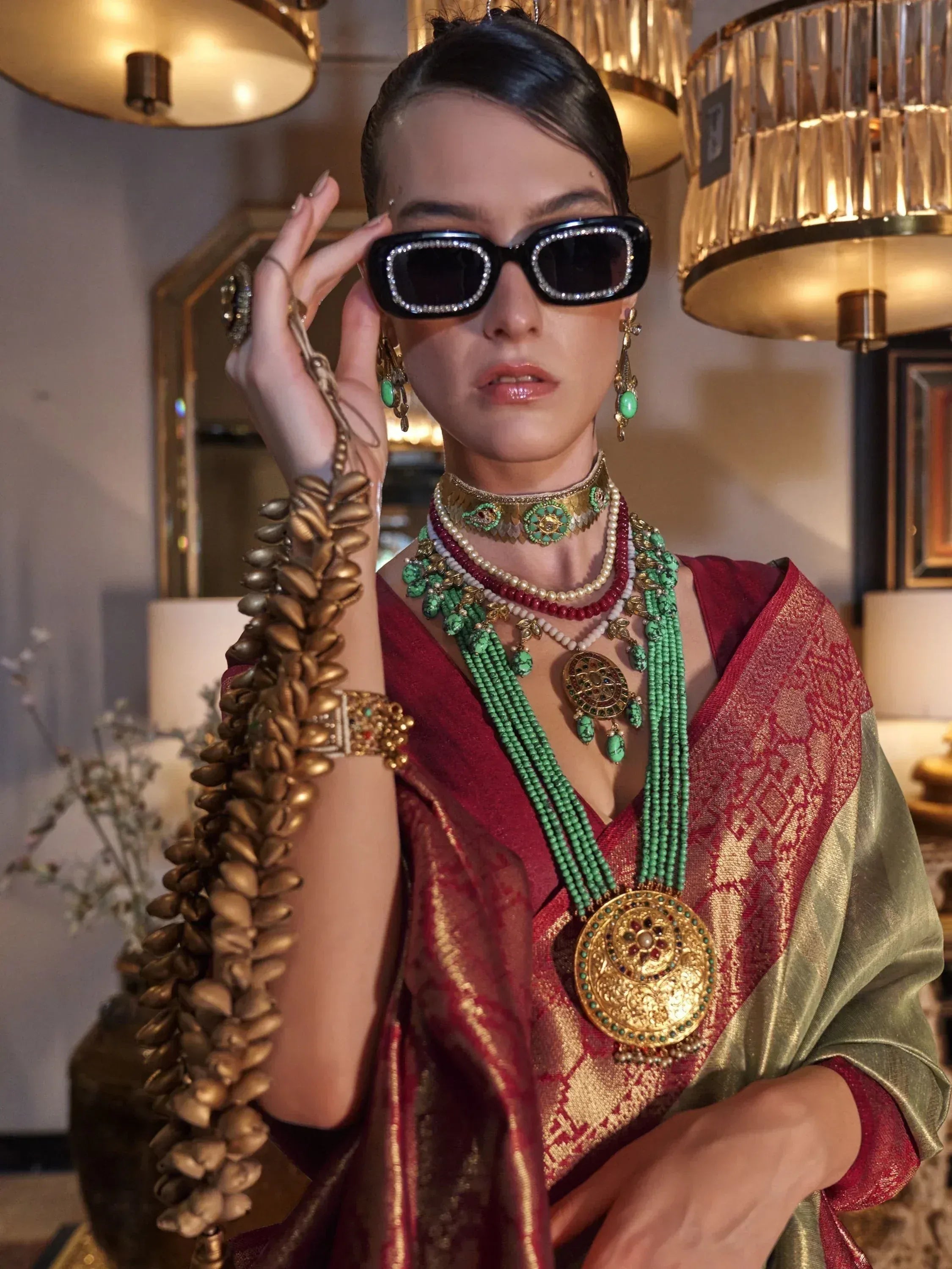 Woman in red and gold ethnic saree with turquoise jewelry and statement sunglasses