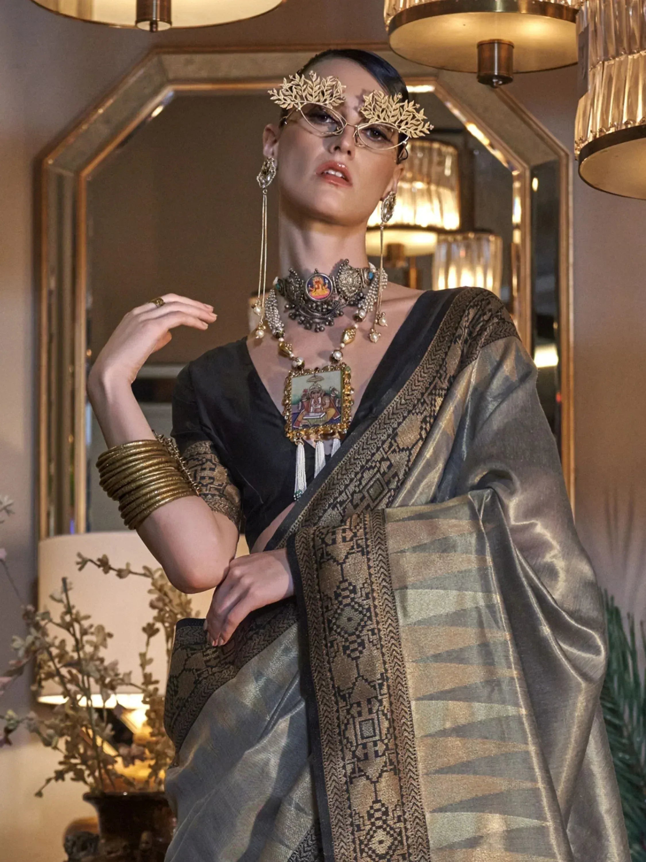 Elegant woman in black and gold ethnic saree with intricate jewelry and traditional headpiece