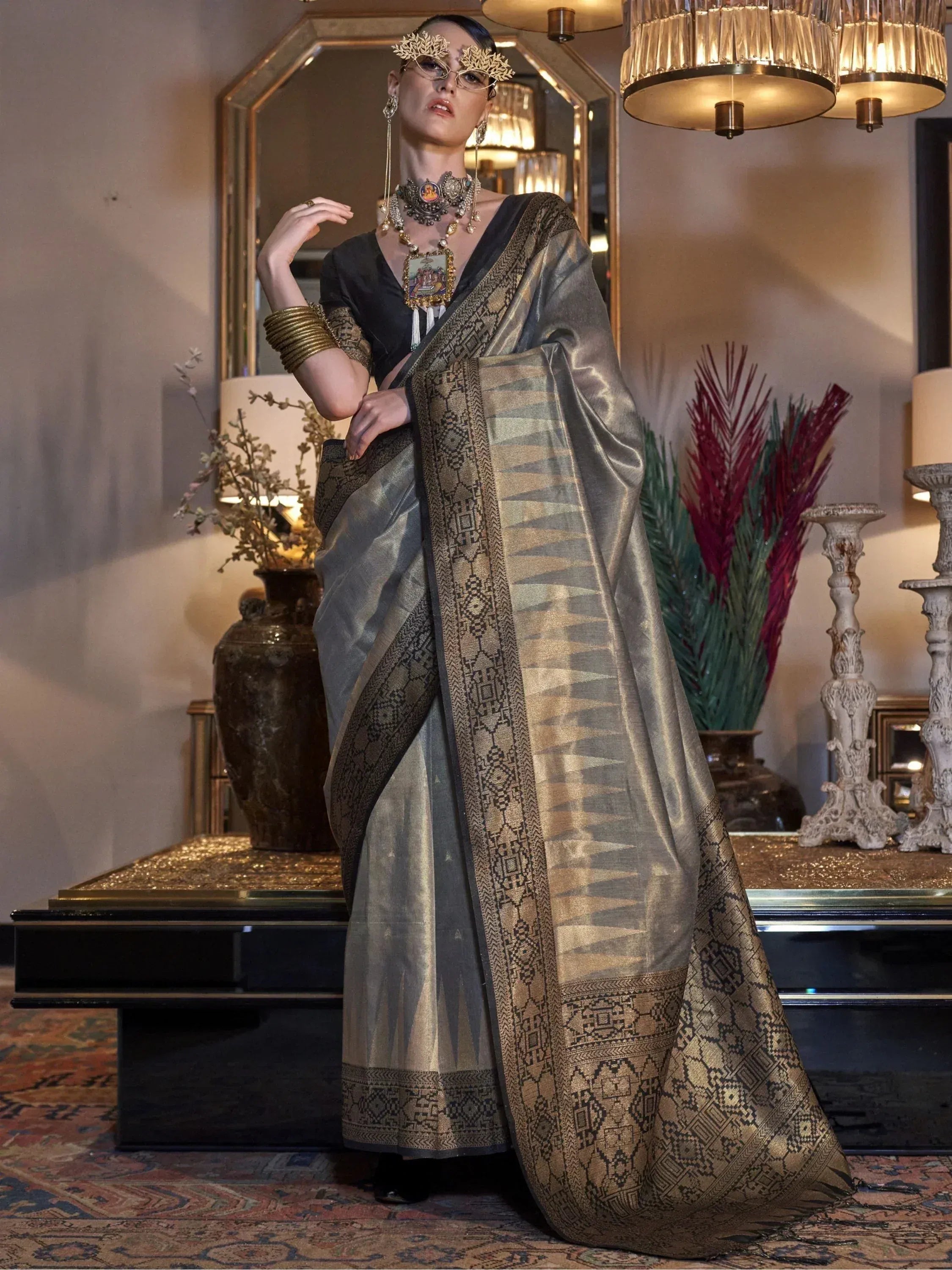 Elegant grey and gold designer saree with intricate geometric border, paired with statement jewelry for ethnic wear