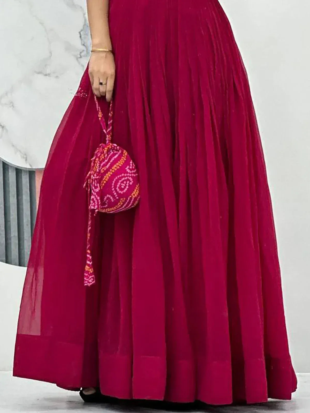 Magenta pleated ethnic gown with embroidered potli bag, perfect for Indian festive occasions