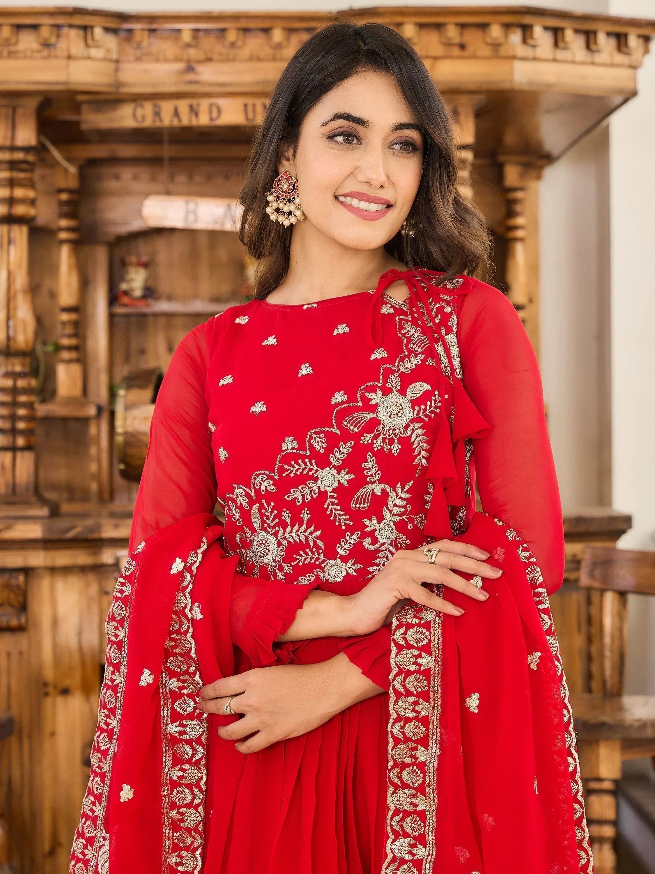 Woman in red embroidered ethnic gown with matching dupatta, traditional Indian wear