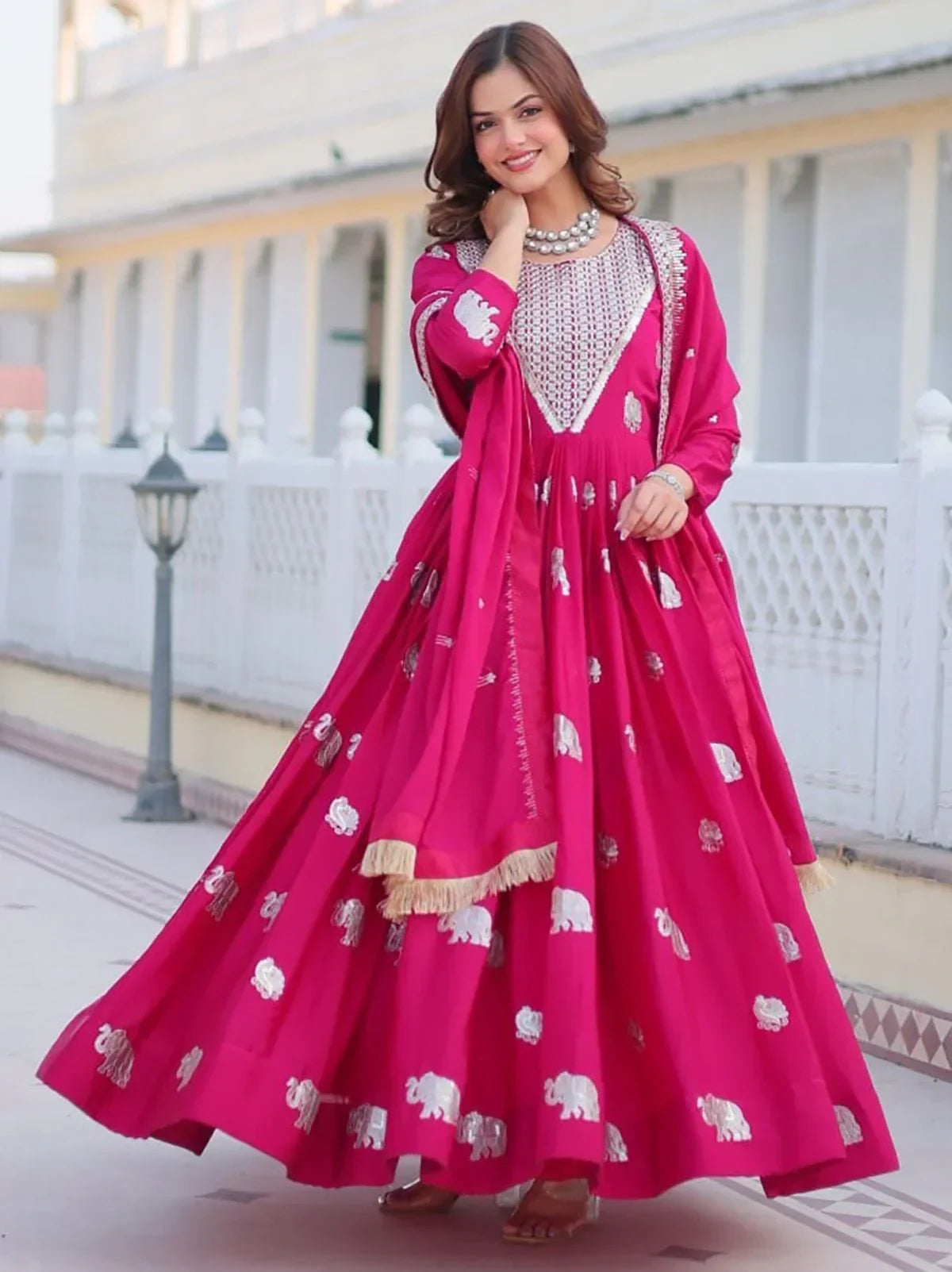 Woman wearing a pink Anarkali gown with white elephant motifs and embroidered dupatta