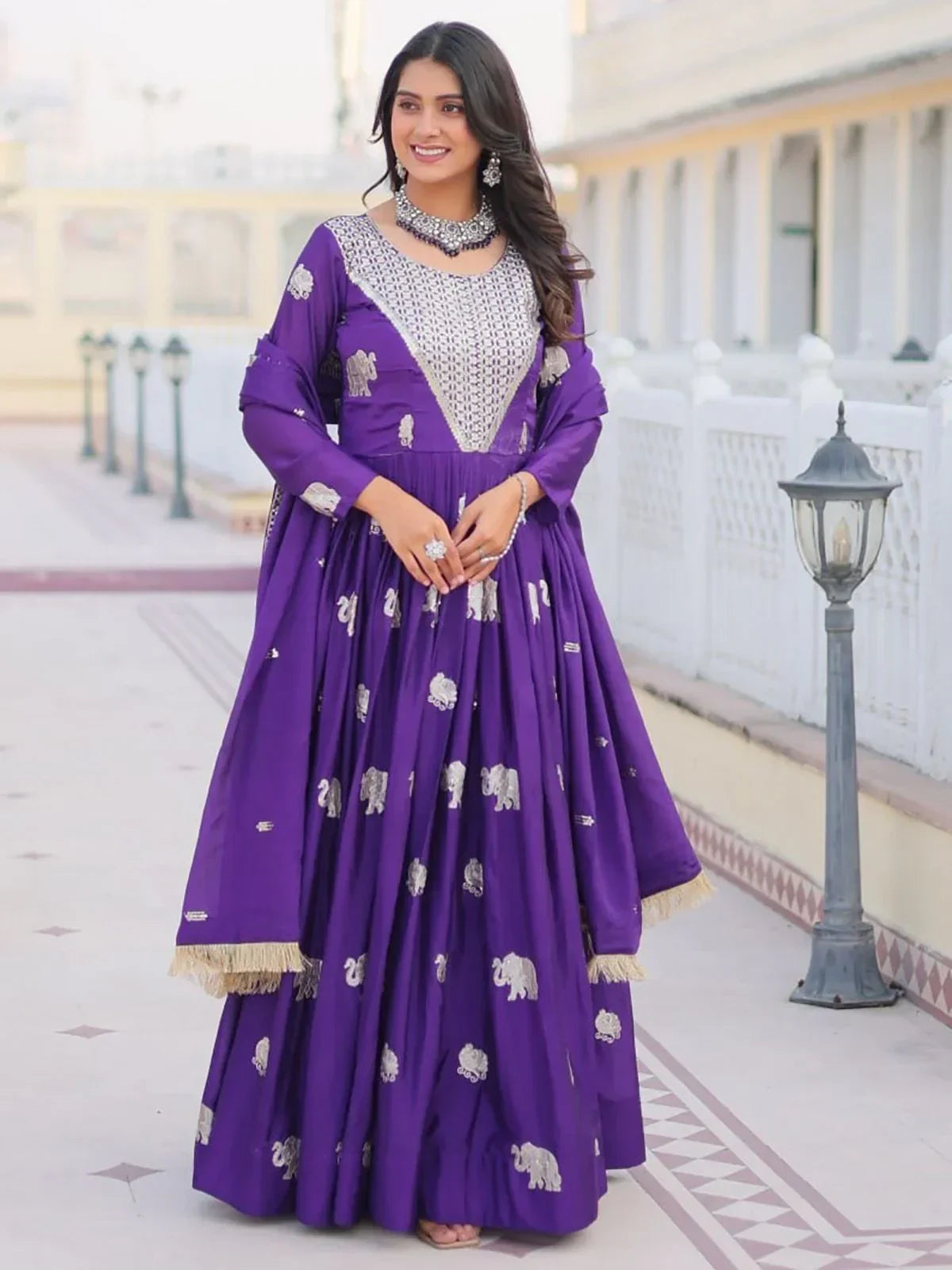 Woman in purple embroidered Anarkali gown with silver elephant motifs, ethnic jewelry, outdoor setting