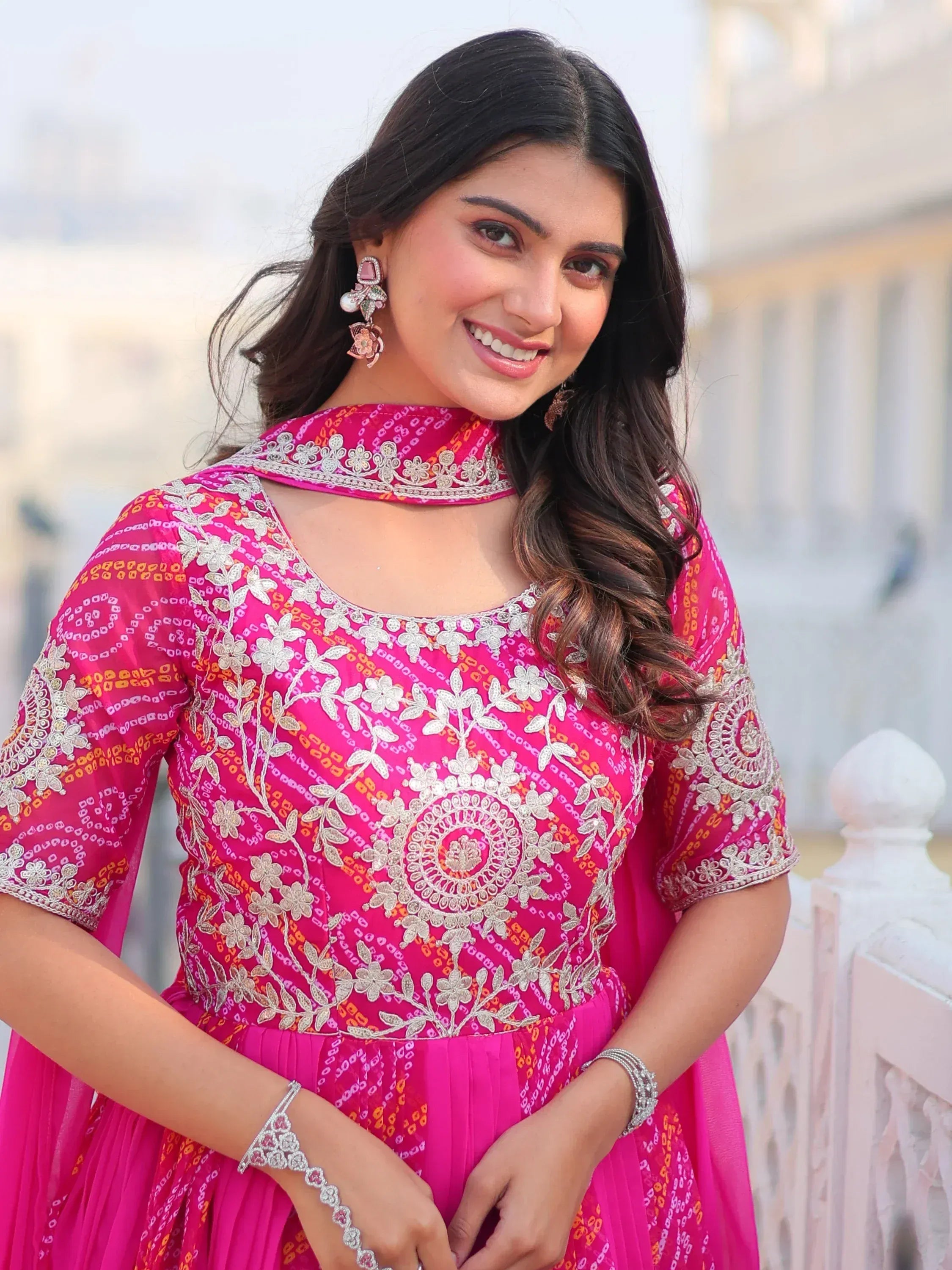 Woman in vibrant pink embroidered ethnic gown with floral patterns and matching jewelry