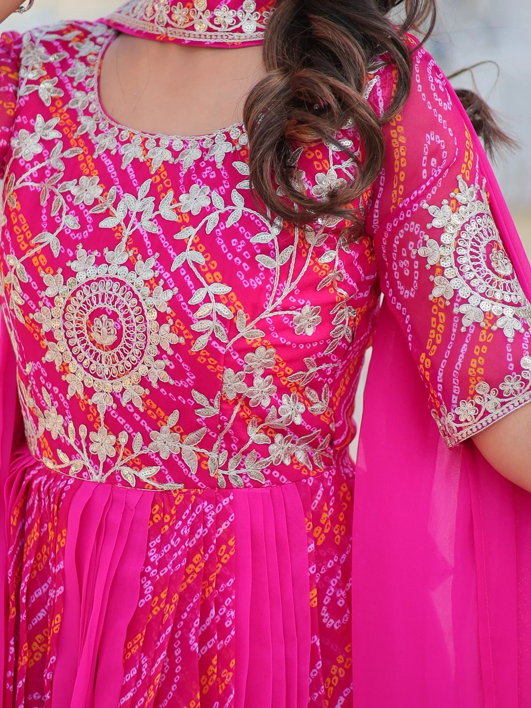 Pink embroidered ethnic gown with floral motifs and pleated skirt, perfect for Indian occasions