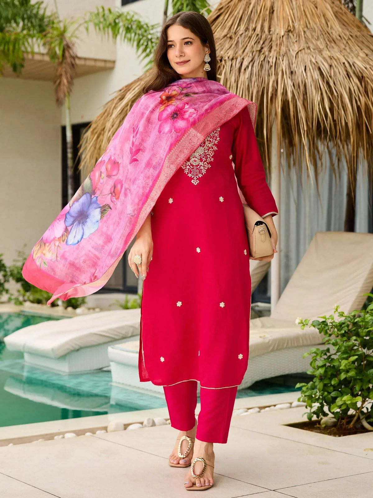 Woman in red embroidered salwar kameez with floral dupatta by poolside, ethnic wear