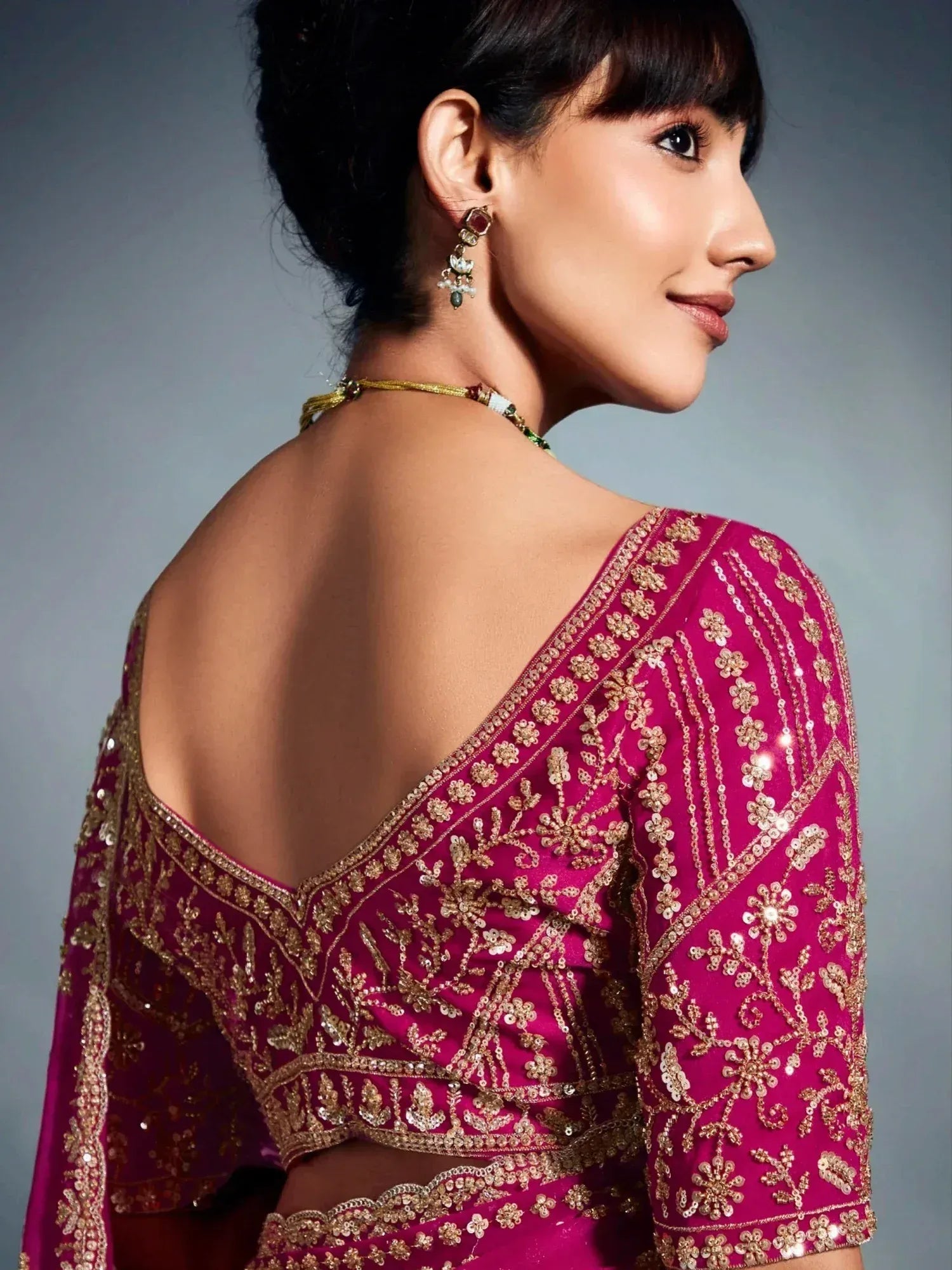Elegant magenta lehenga choli with gold floral embroidery and open back design, perfect for Indian ethnic wear.
