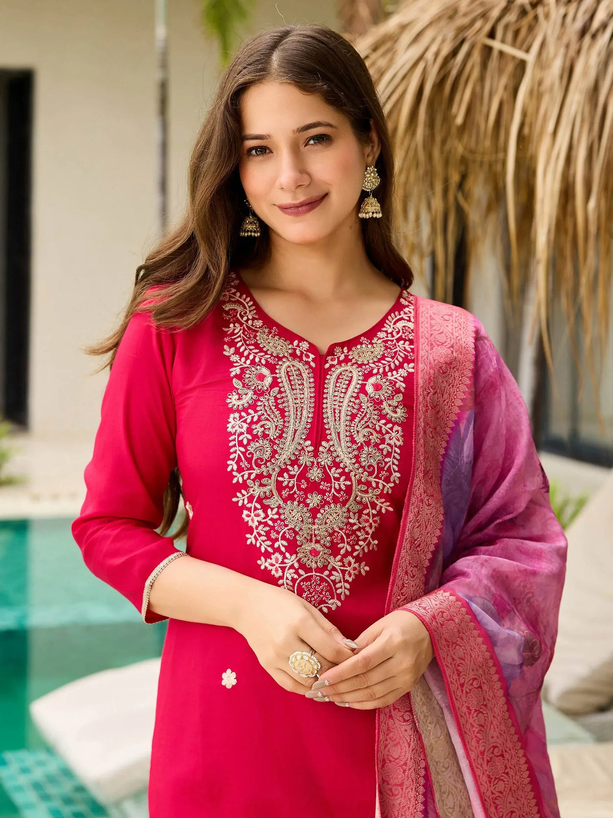 Woman in pink embroidered salwar kameez with dupatta, poolside setting