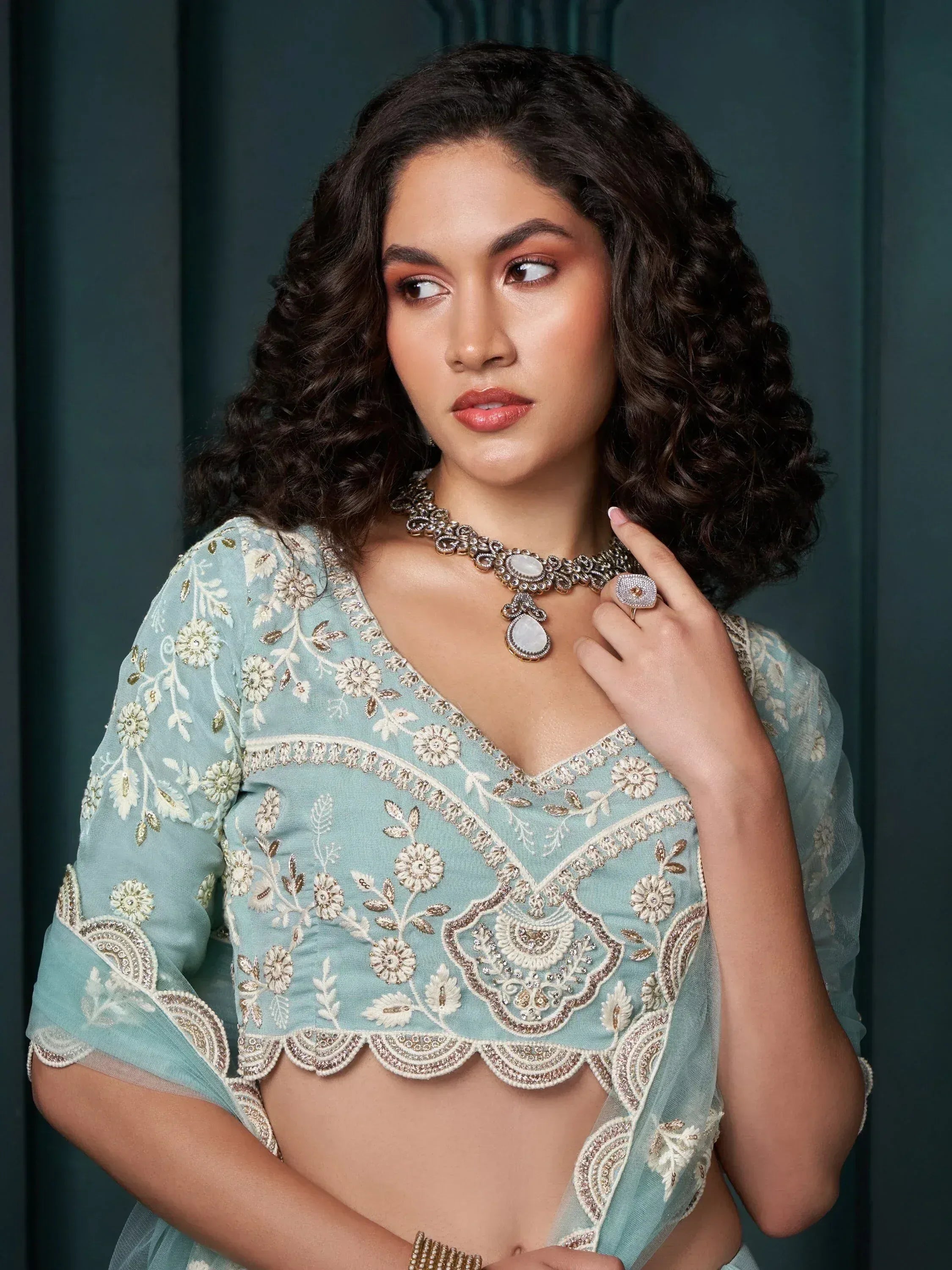 Woman in light blue embroidered ethnic blouse with floral detailing and statement jewelry