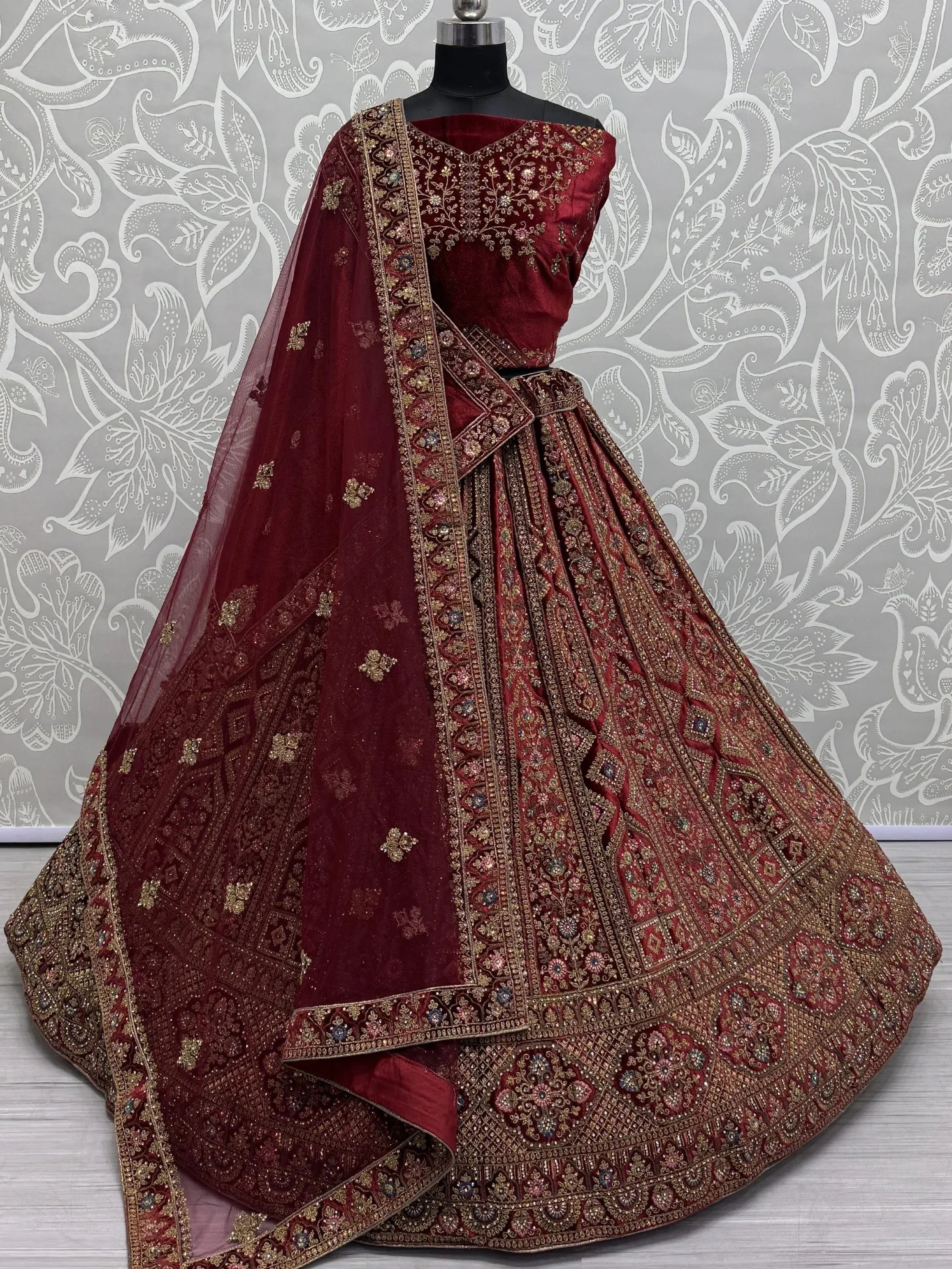 Maroon velvet designer lehenga choli with heavy gold embroidery and matching dupatta, ideal for weddings